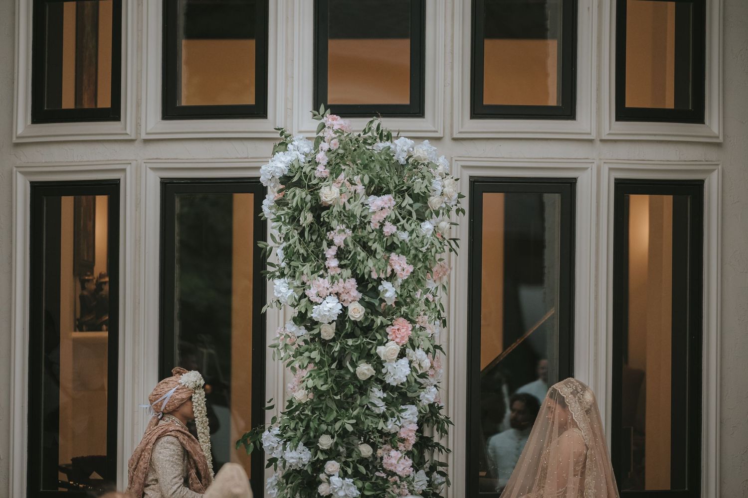 Delicate white floral arrangements adorn a bay window with illuminated window panes behind them.