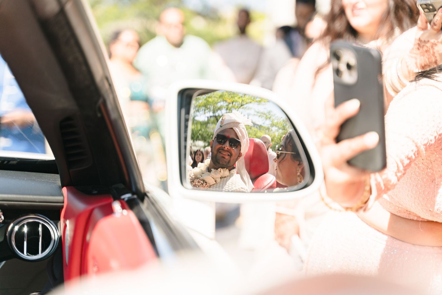 Car side mirror reflection capturing wedding day moment outdoors.