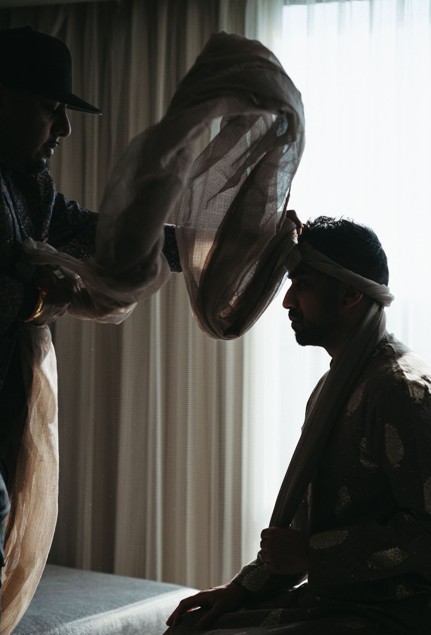 Silhouetted figures preparing for a traditional ceremony or ritual in a dimly lit room.
