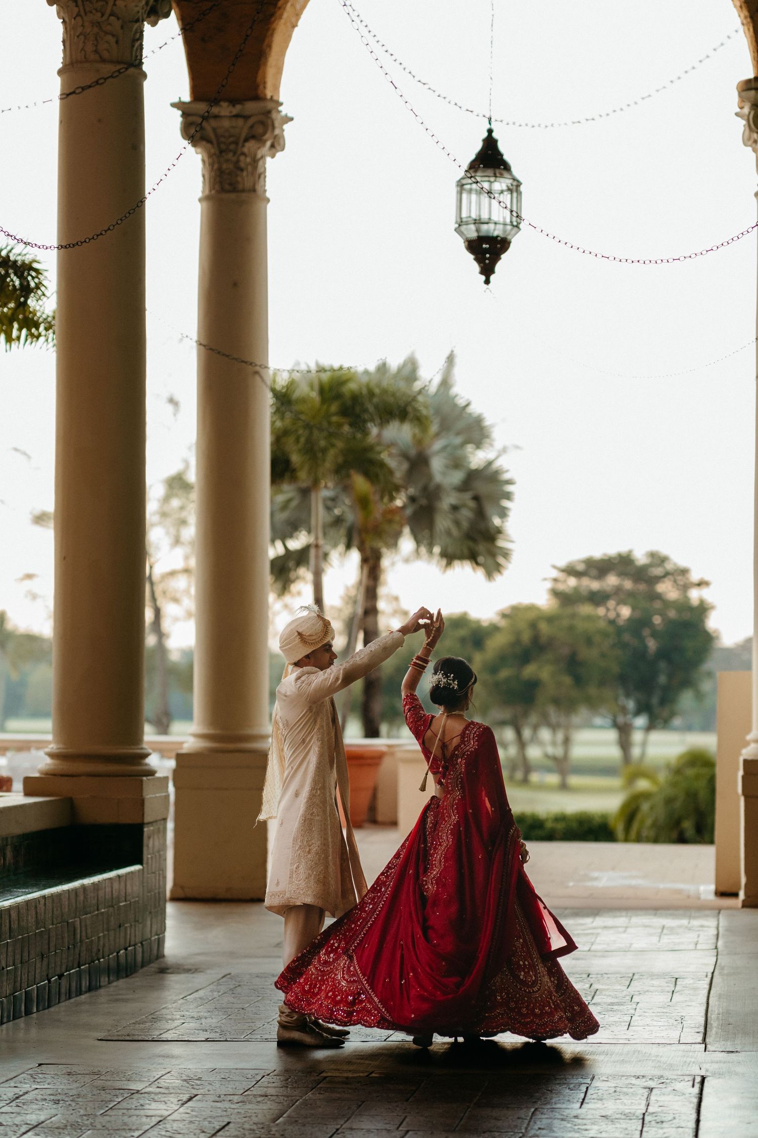 Couple dancing under ornate archway with hanging lantern at luxury venue.