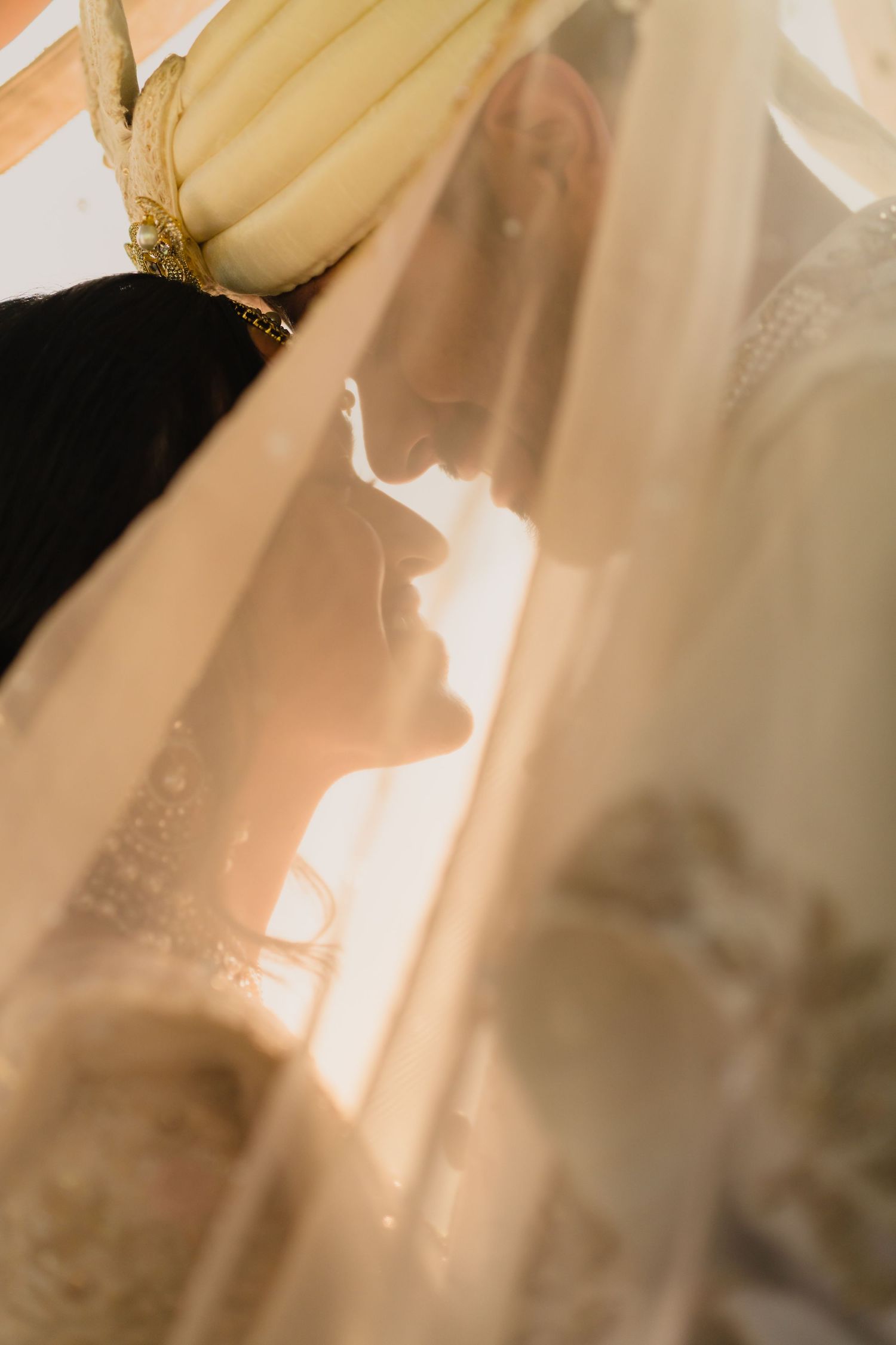 Artistic silhouette through sheer fabric with soft warm lighting.