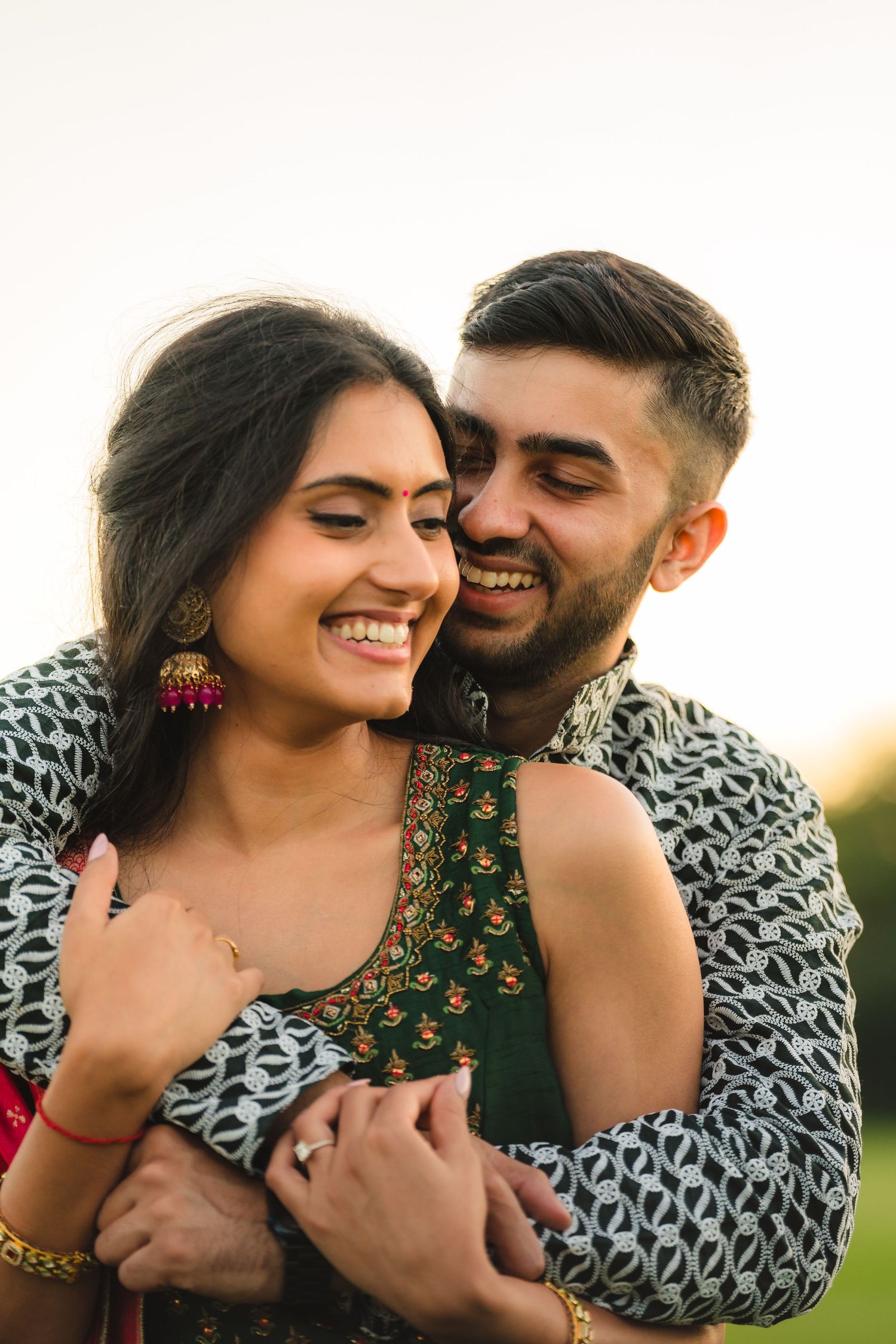 A romantic couple shares an intimate moment outdoors, wearing South Asian inspired clothing and jewelry.