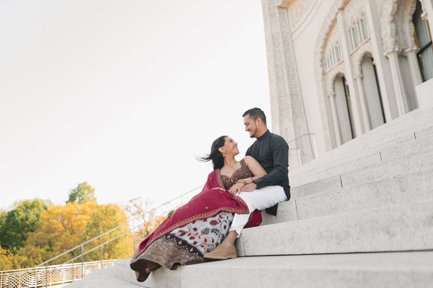 Romantic pose on grand white marble steps of ornate classical architecture.