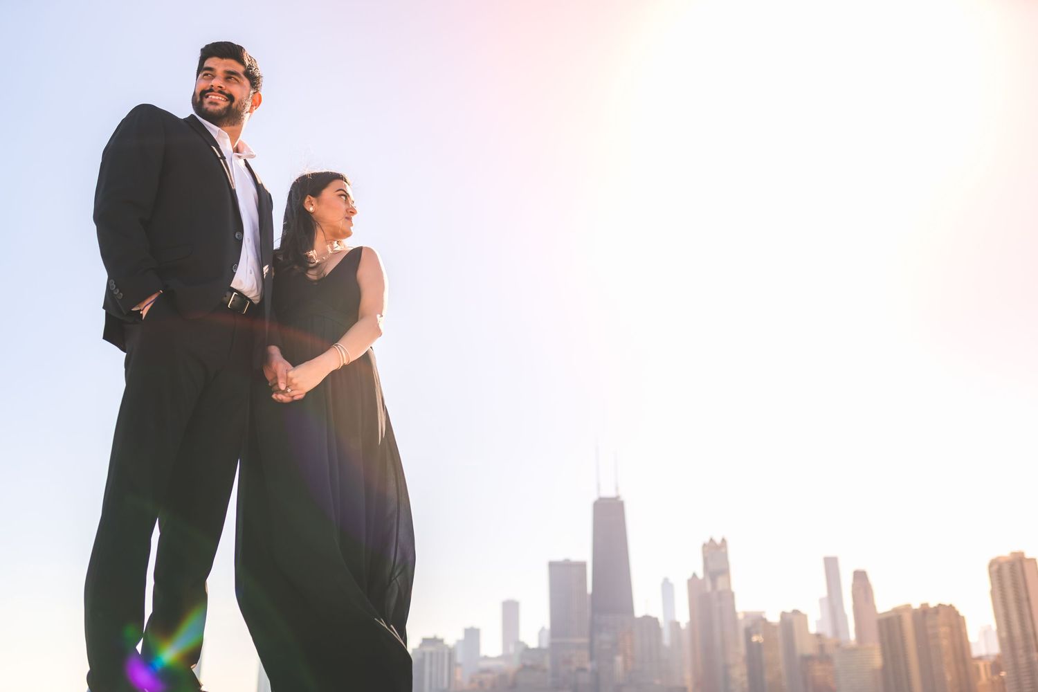 A silhouetted couple stands against Chicago skyline at sunset.