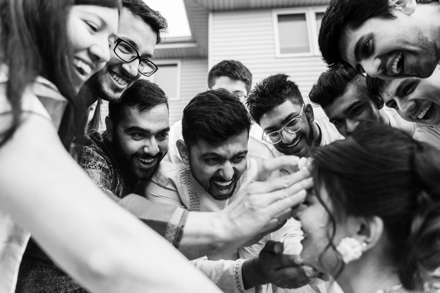 A candid black and white photo of a joyous group celebration at a wedding.