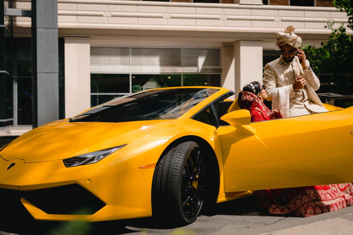 A bright yellow Lamborghini Huracan convertible parked in front of a modern building.
