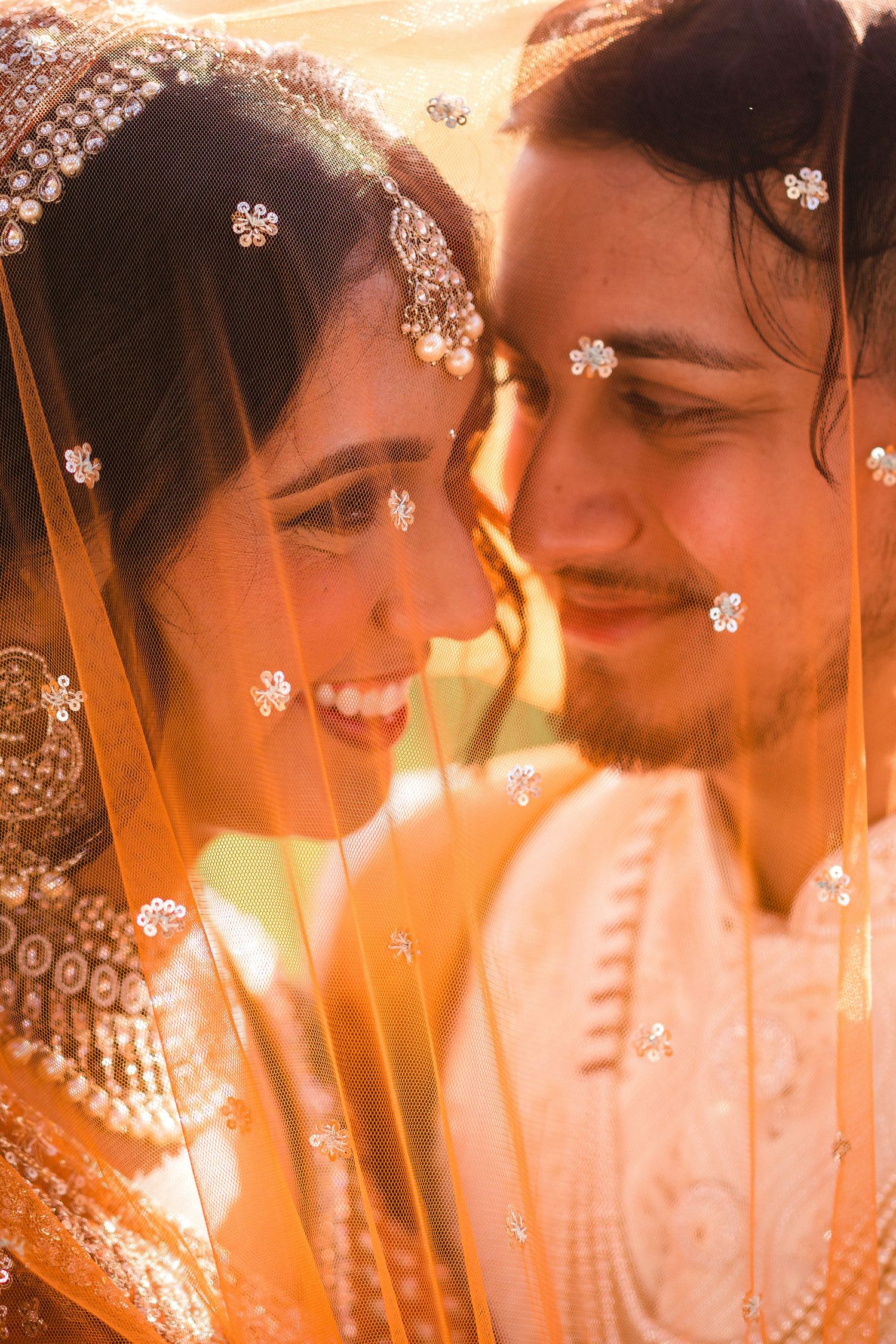 Close-up of a traditional Indian wedding couple sharing an intimate moment in warm sunset lighting, adorned with bridal jewelry.