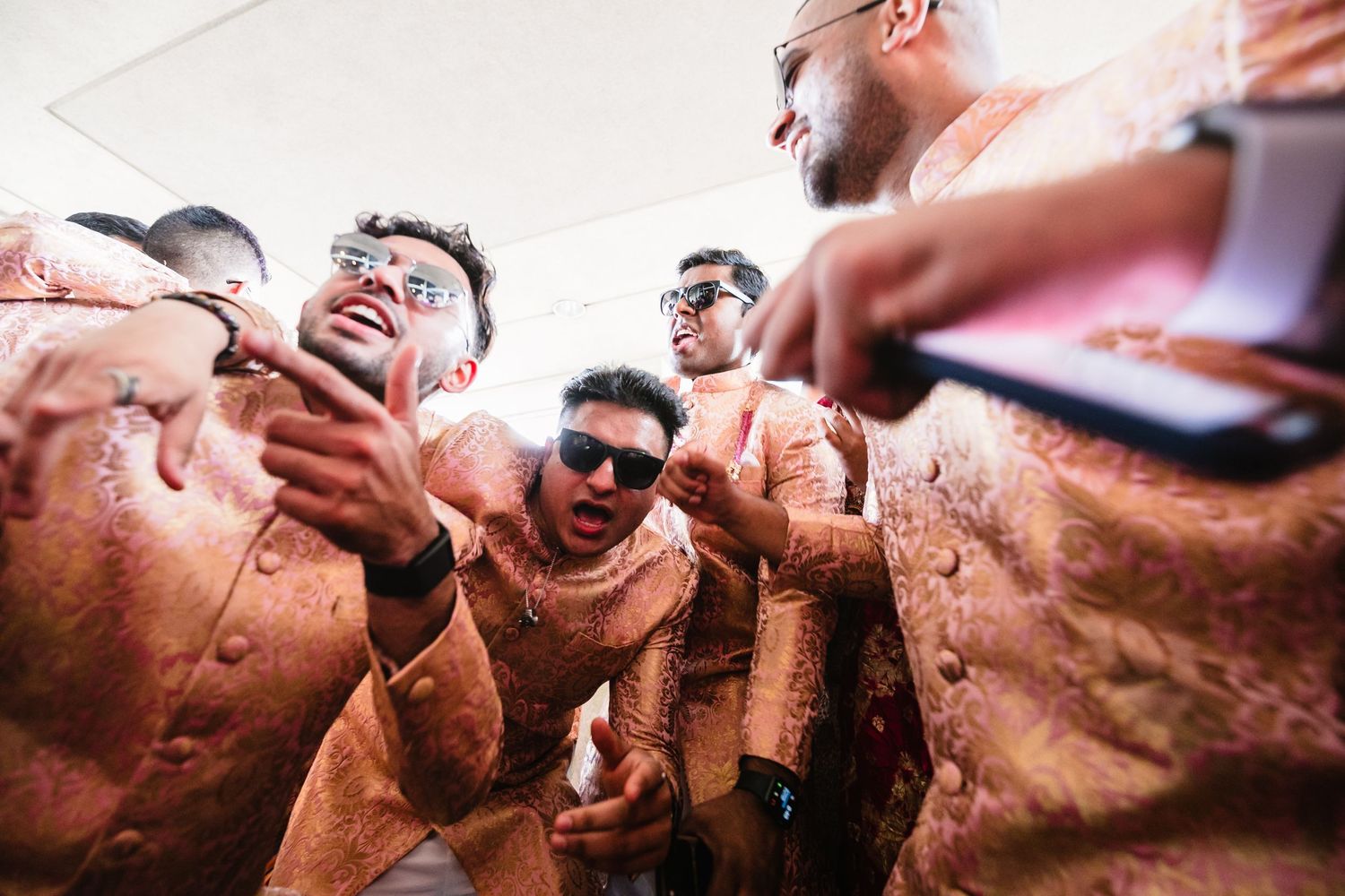 Groomsmen sharing laughter during wedding celebrations in matching outfits.