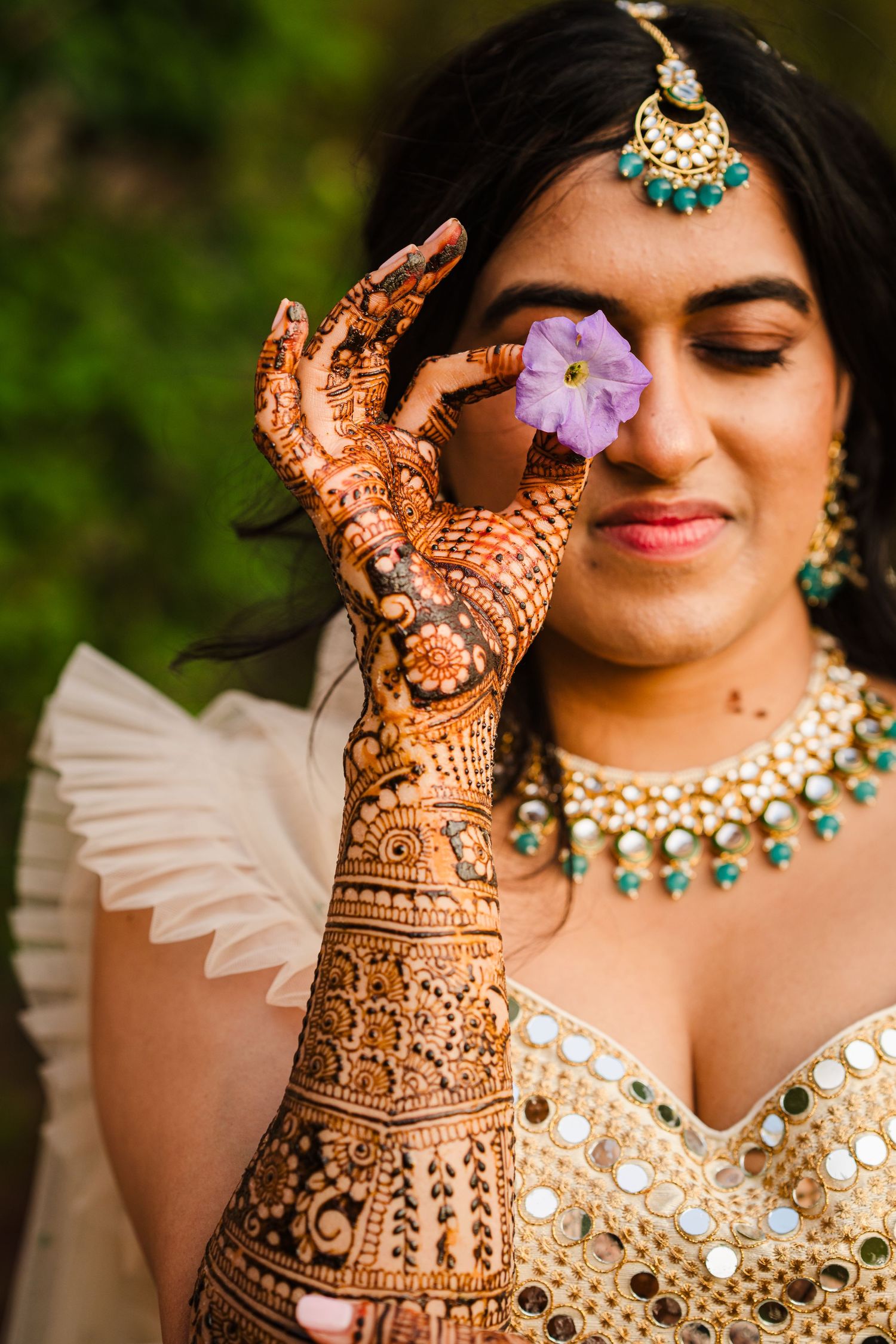 Traditional Indian bridal jewelry and henna design with purple flower detail.