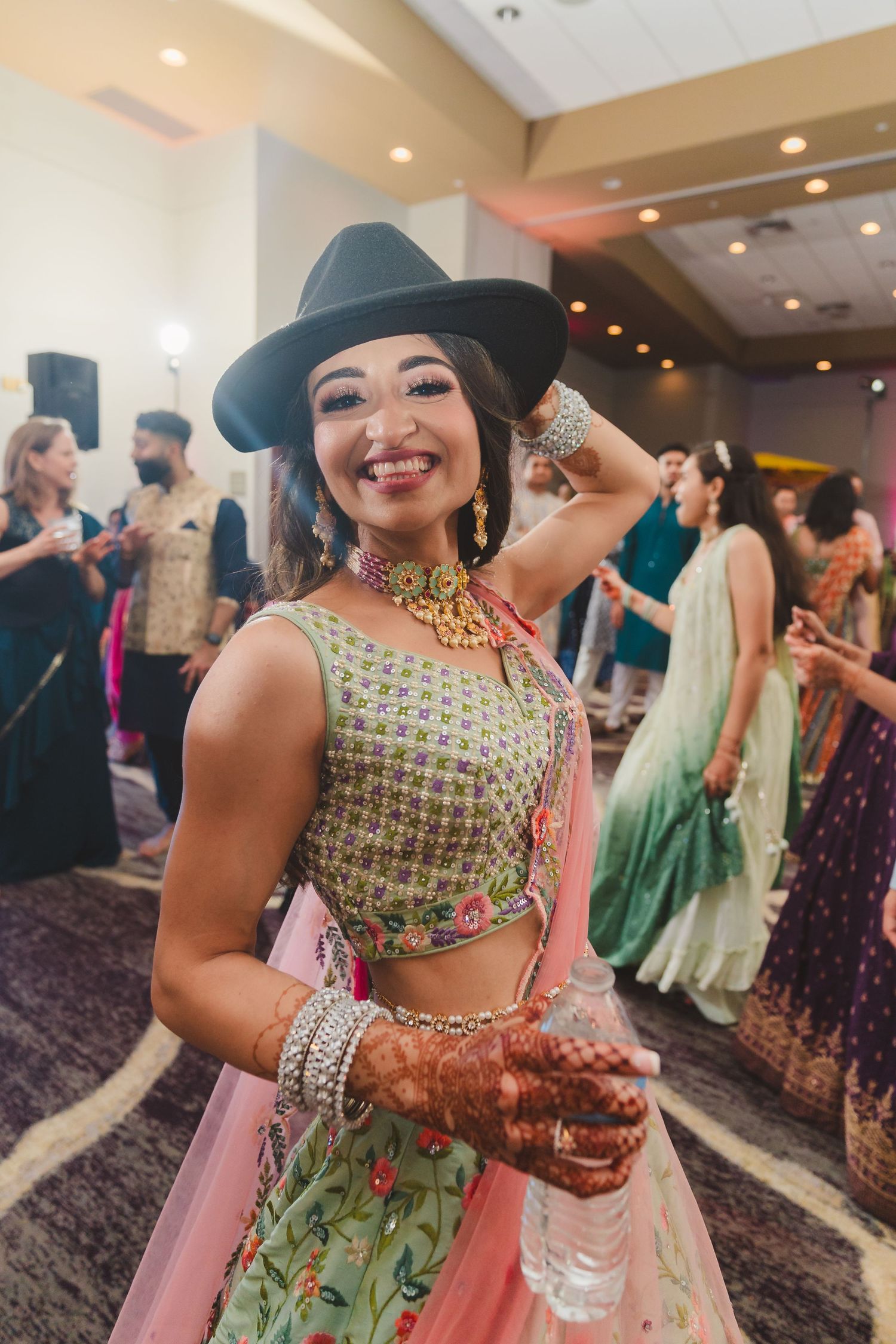 Festive celebration scene with dancer wearing traditional Indian fusion outfit and hat.