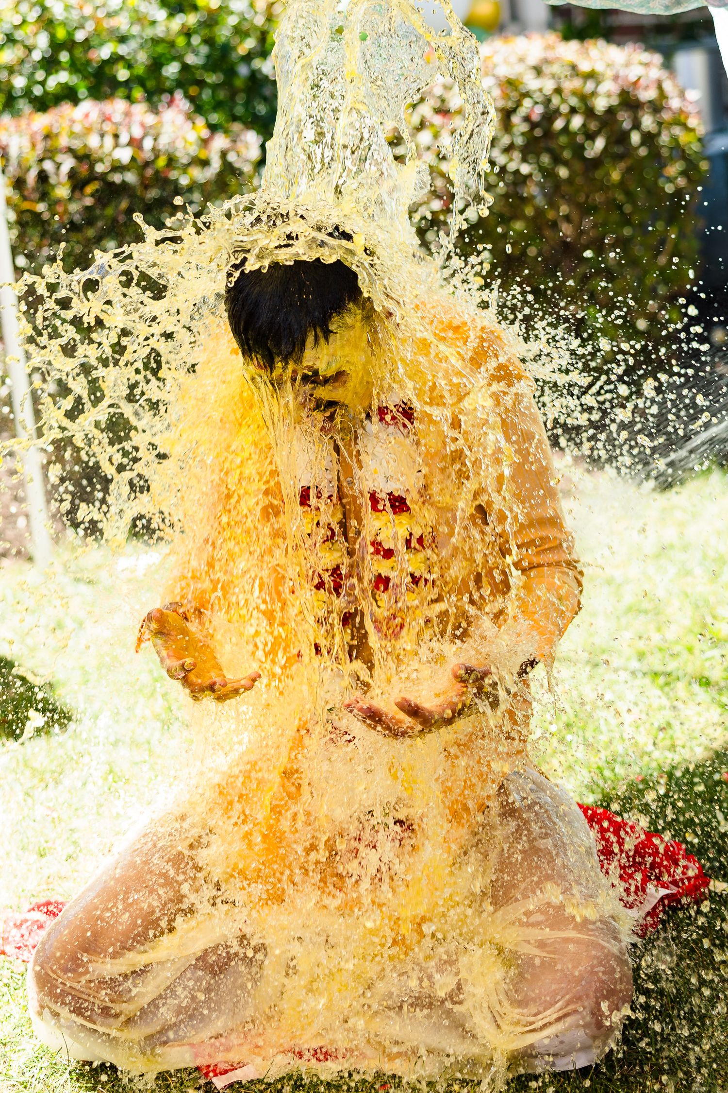 A vibrant splash of yellow water creates a dramatic effect as it cascades down in an outdoor garden setting.