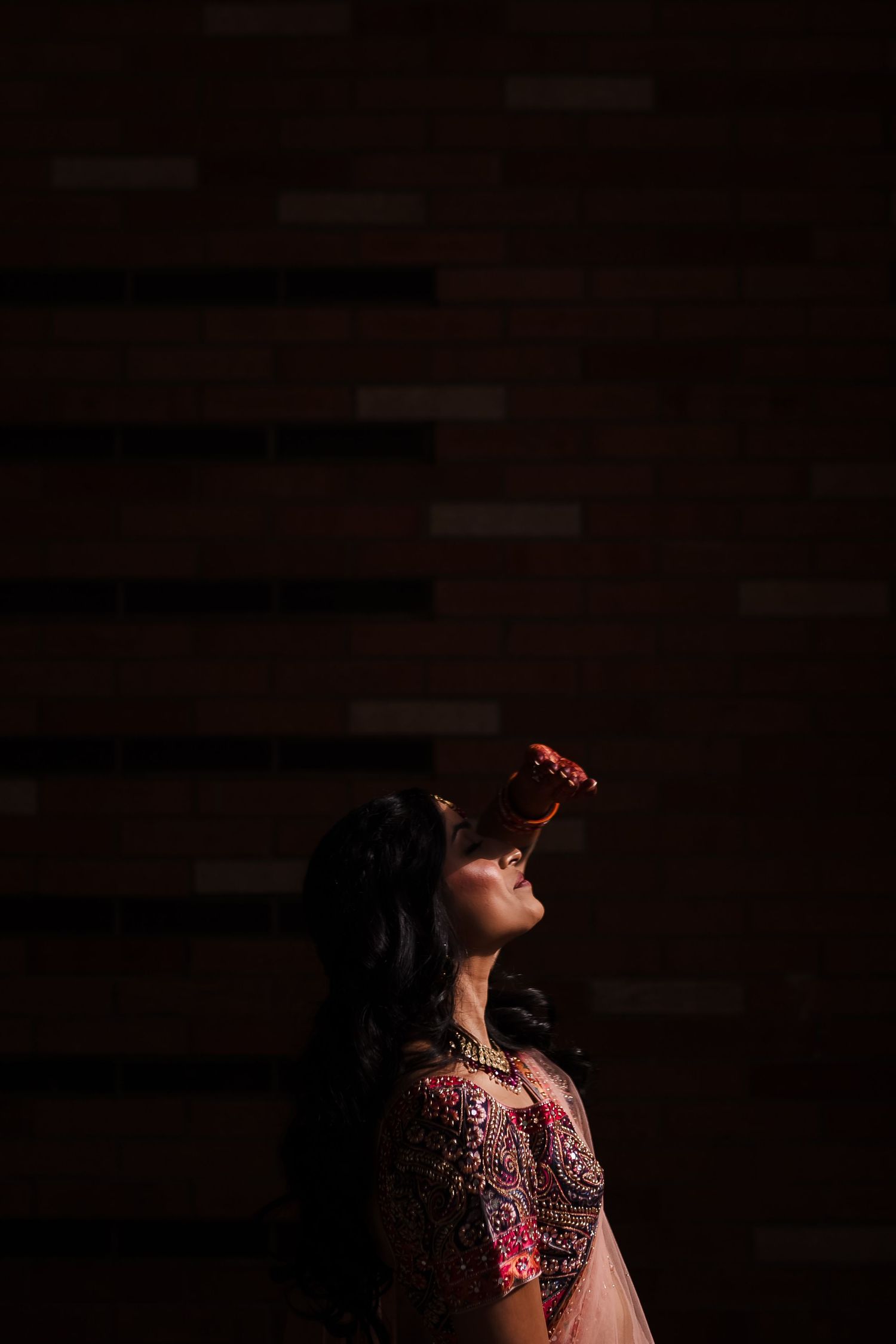 Dramatic silhouette of person in Indian wedding attire against dark background.