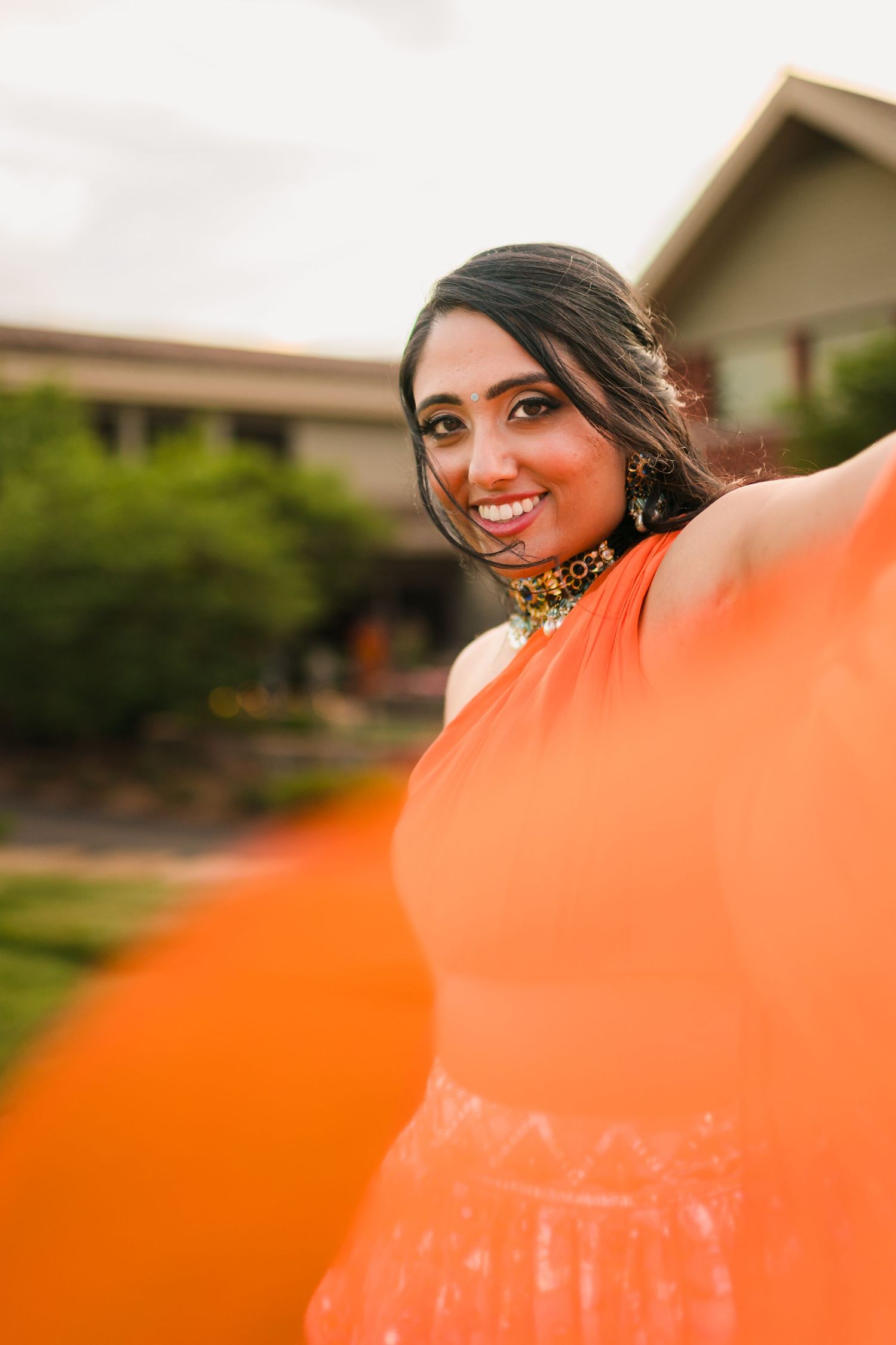 Beautiful portrait in orange evening light with traditional Indian jewelry and warm golden tones.