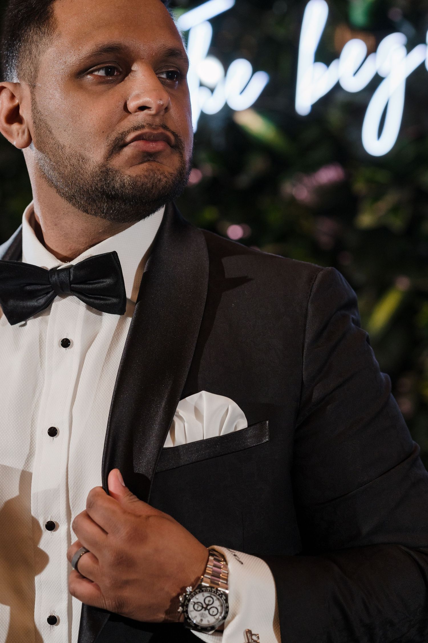 Formal attire with black bow tie and white pocket square against illuminated background.
