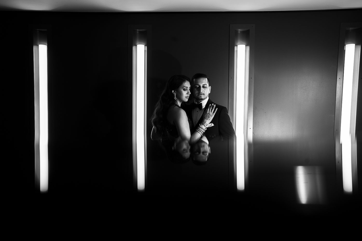 A dramatic black and white portrait illuminated by vertical light bars against a dark background.