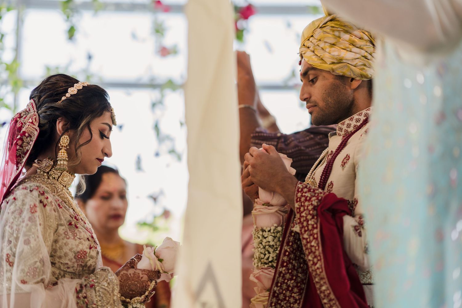 Traditional Indian wedding ceremony with couple performing cultural rituals under decorated mandap.