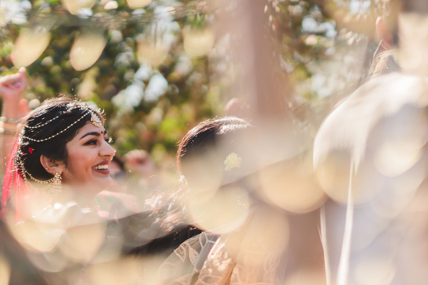 Candid wedding moment captured through bokeh lights and decorations.