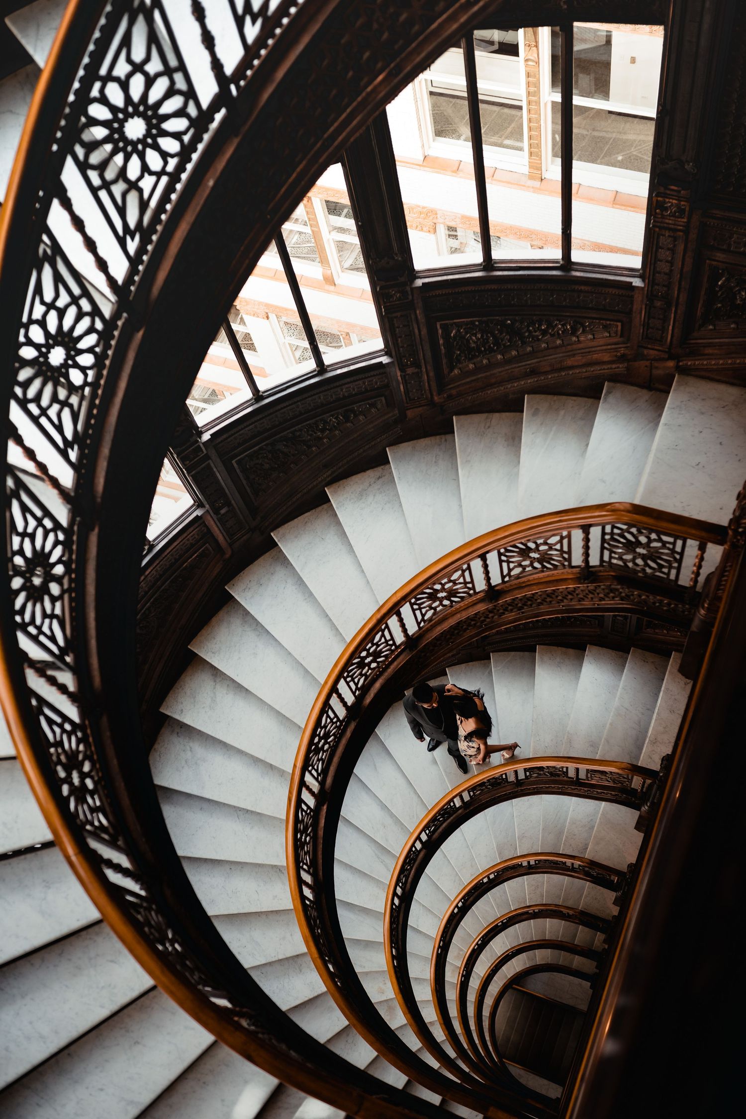 View down a spiral staircase with ornate wrought iron railings and white steps creating a mesmerizing pattern.