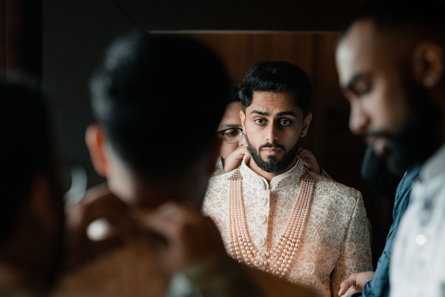 Traditional Indian groom wearing an ornate white sherwani at a wedding ceremony.