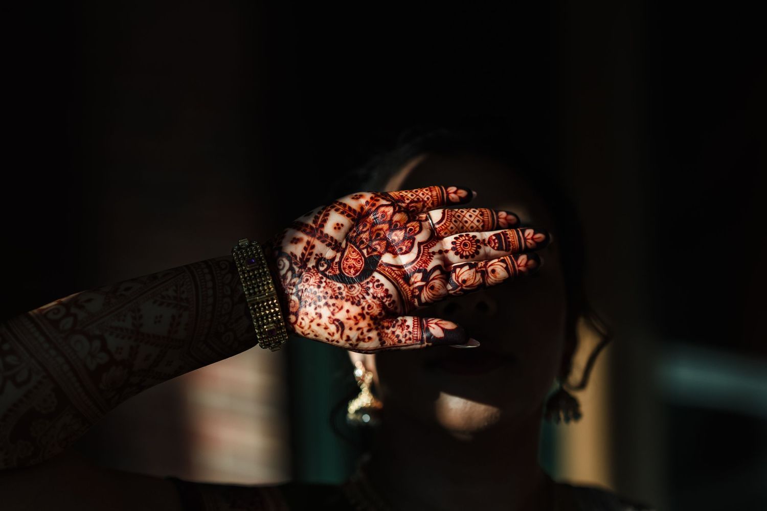 Intricate henna designs adorning hands in traditional Indian mehndi art style captured in dramatic lighting.