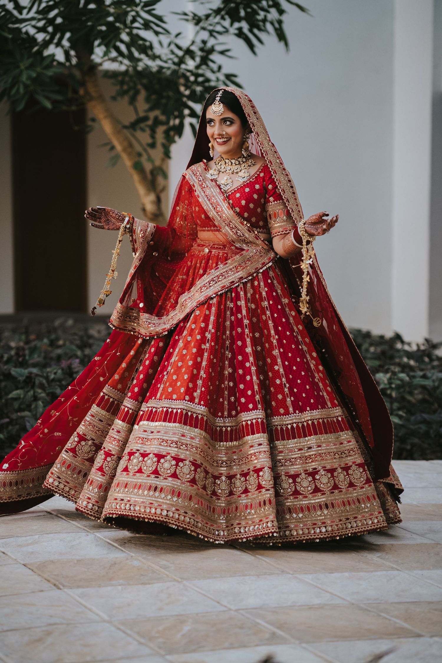Traditional red and gold Indian wedding lehenga with intricate embroidery and detailed border work.