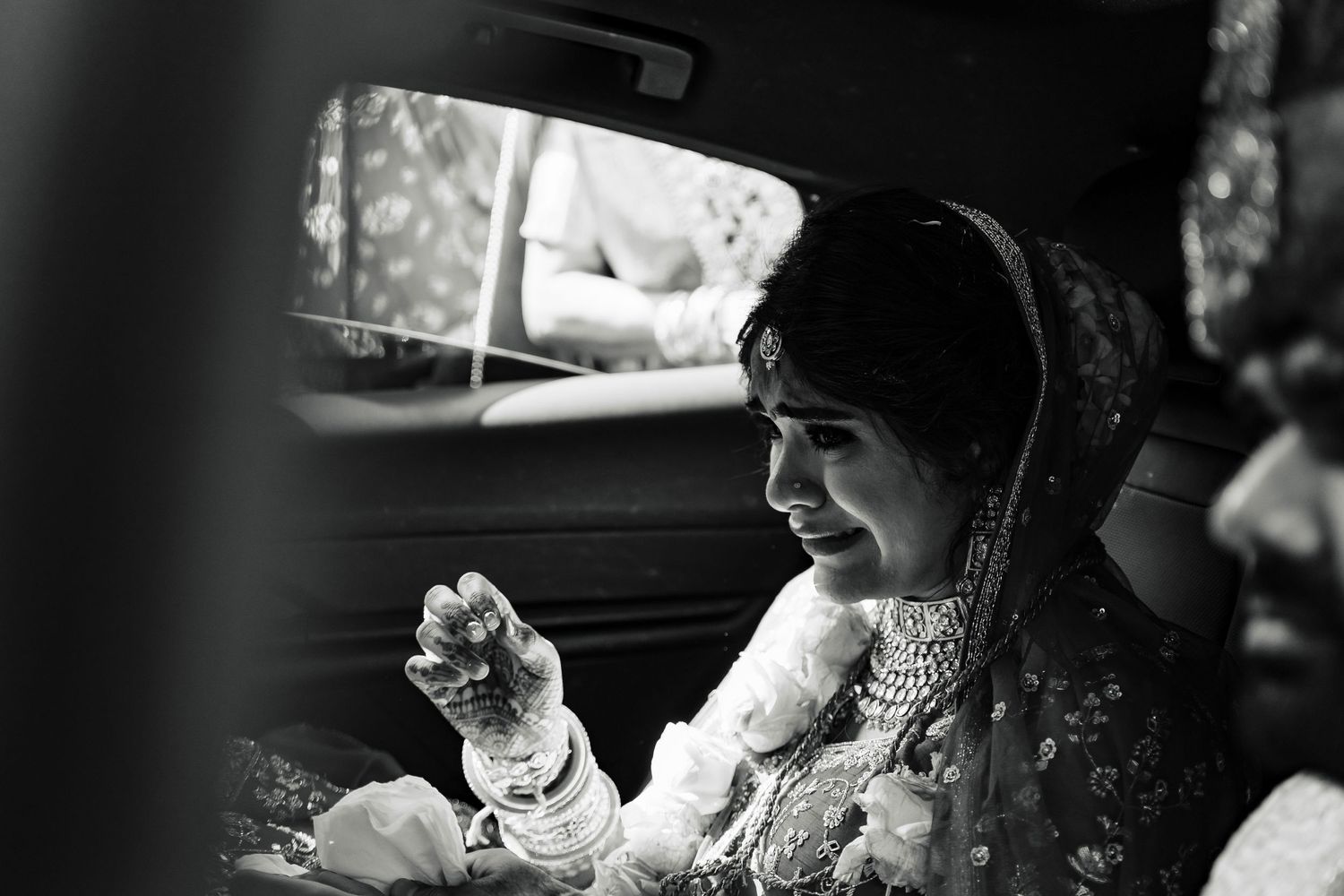 Black and white portrait of person in traditional wedding attire inside car.
