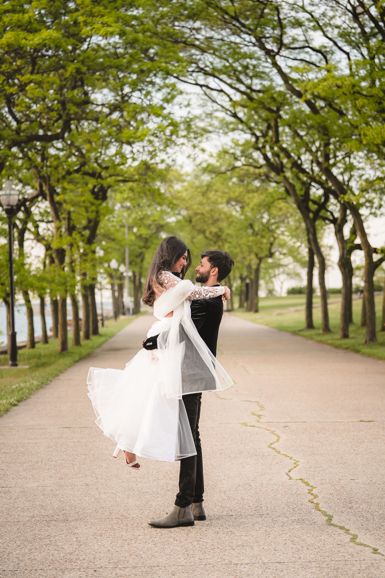 A romantic moment on a tree-lined path with flowing white dress.