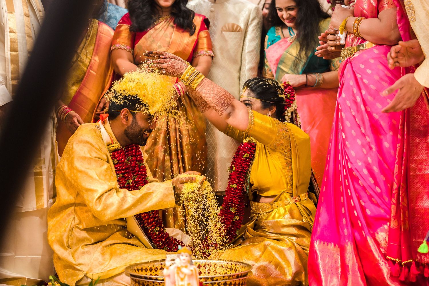 Traditional Indian wedding ritual with yellow and gold clothing and flower decorations.