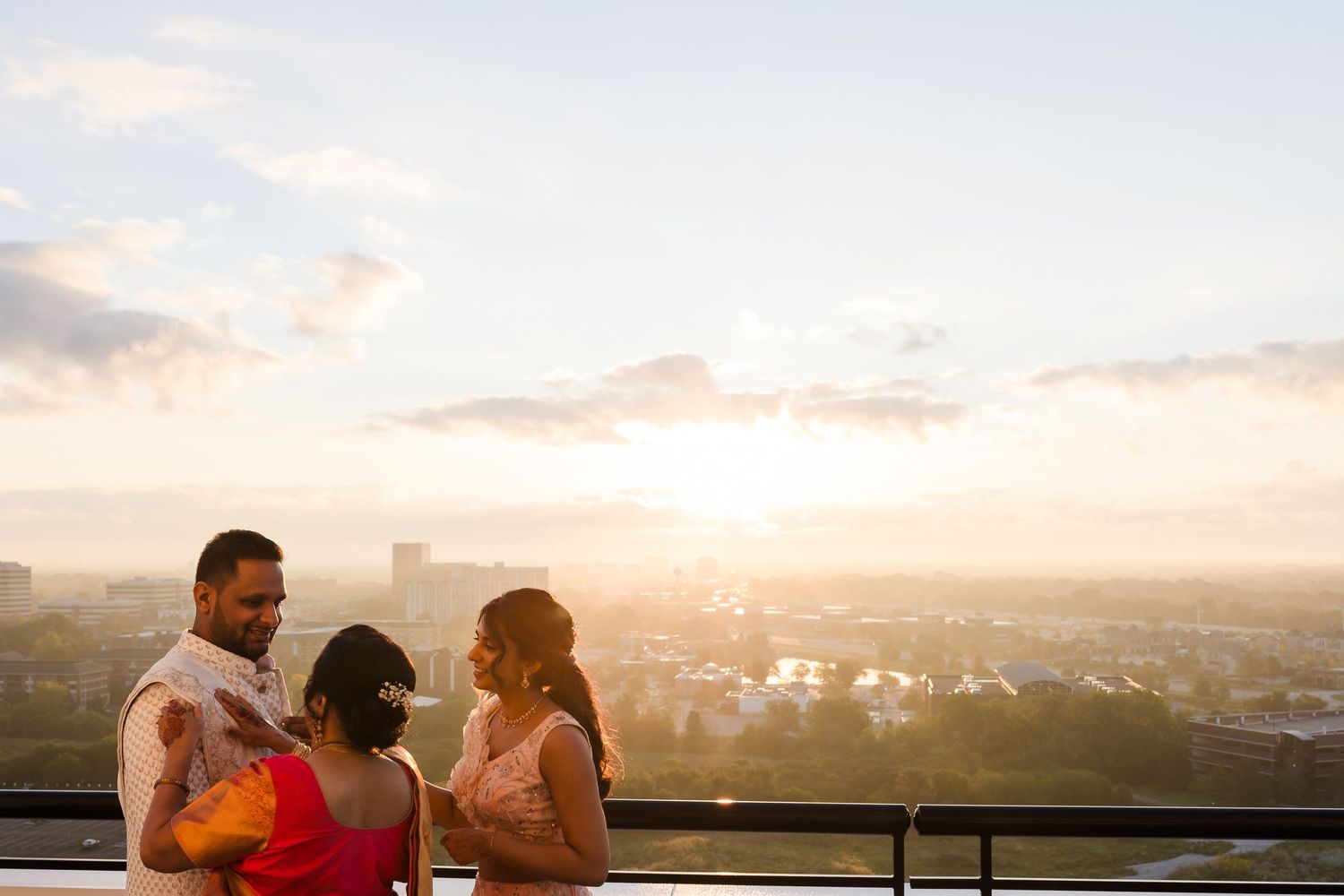 People enjoying a sunset view from a rooftop balcony overlooking a cityscape.