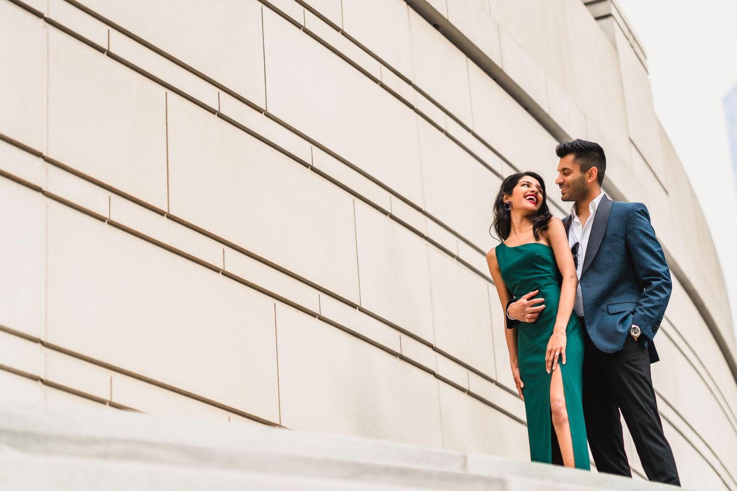 Elegant couple poses against modern white geometric architecture with dramatic angles.