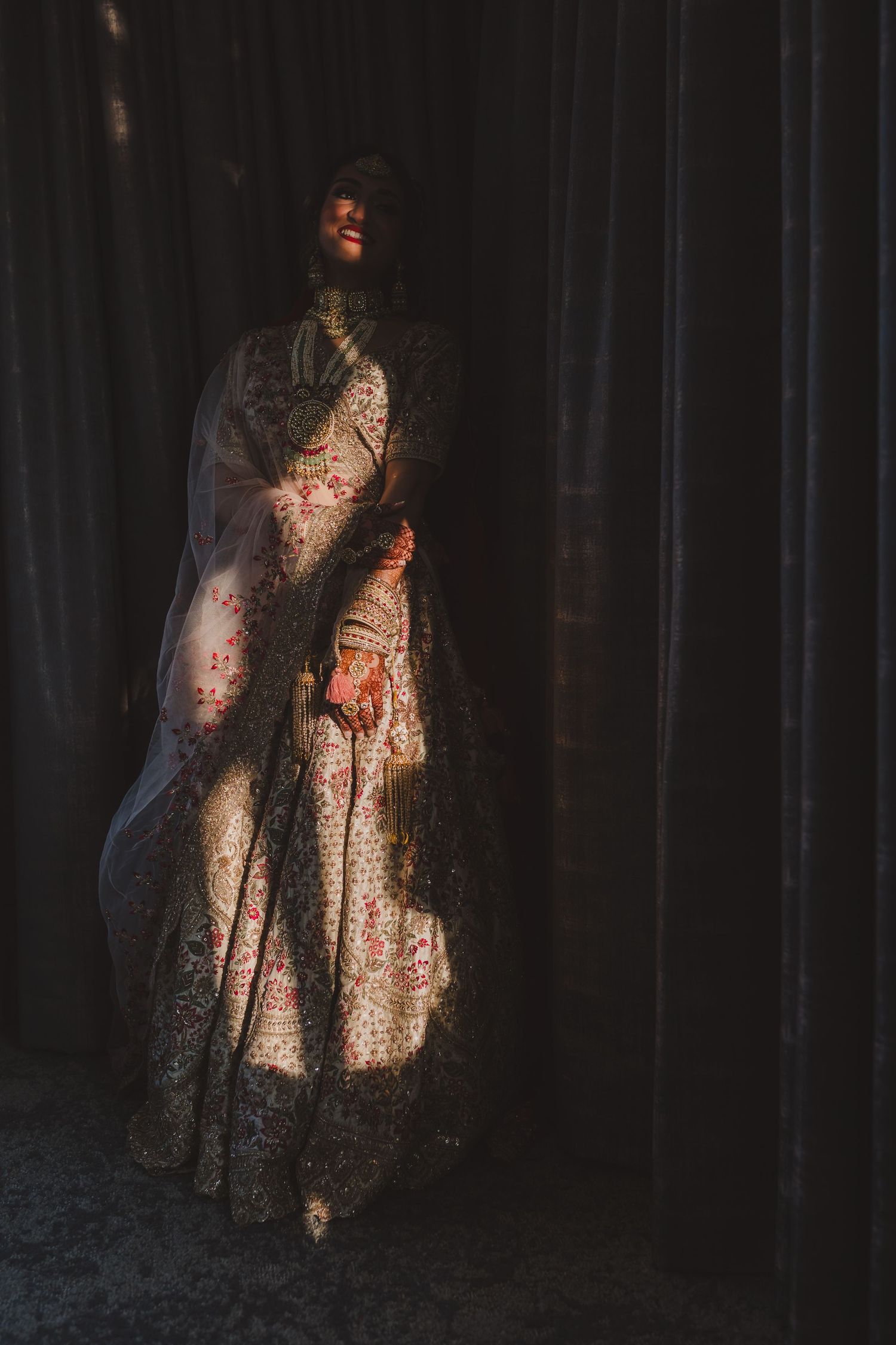 A silhouette figure in an ornate dress poses dramatically against dark curtains with dramatic lighting.