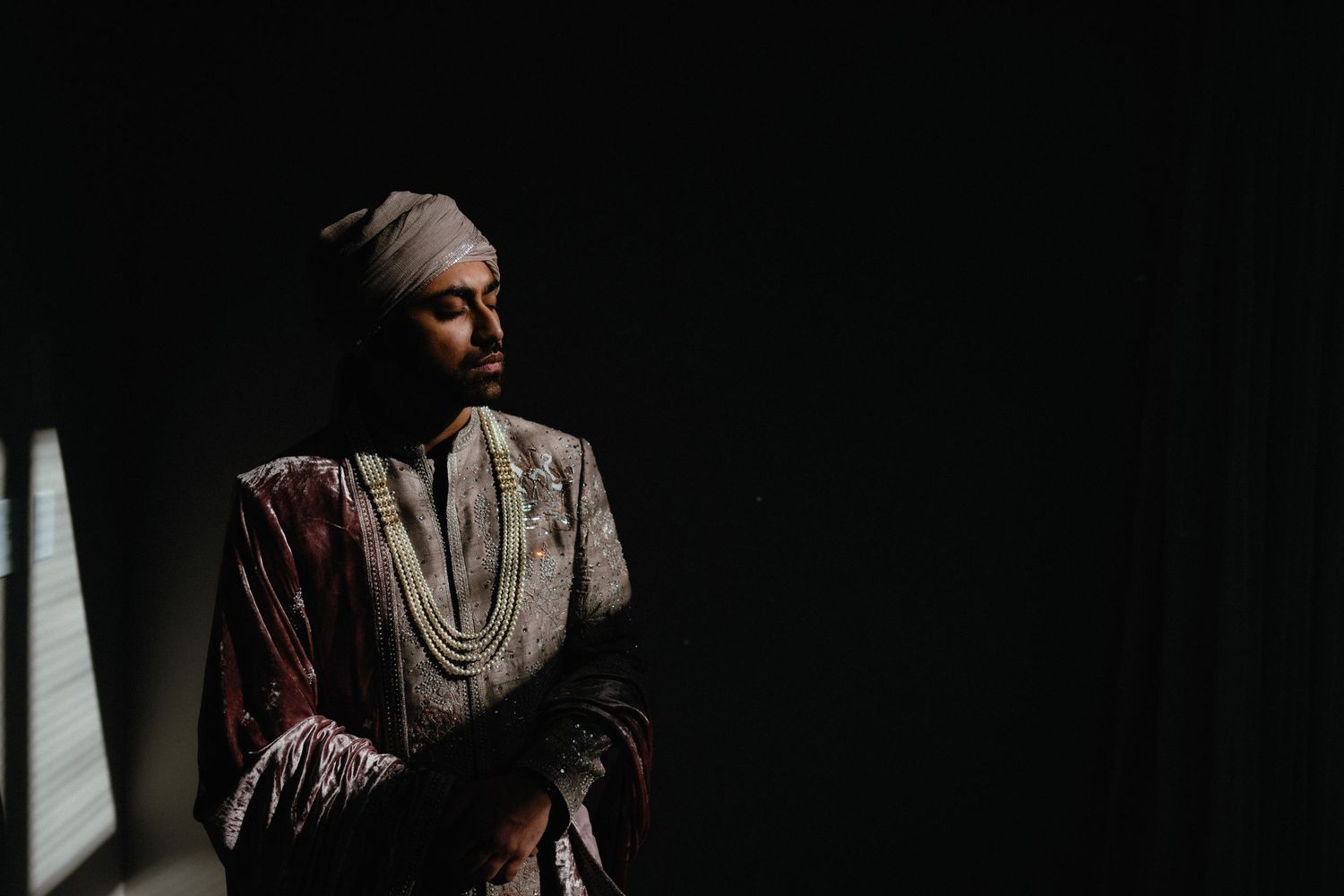 A silhouetted figure in traditional African dress stands against a dark background with dramatic side lighting.