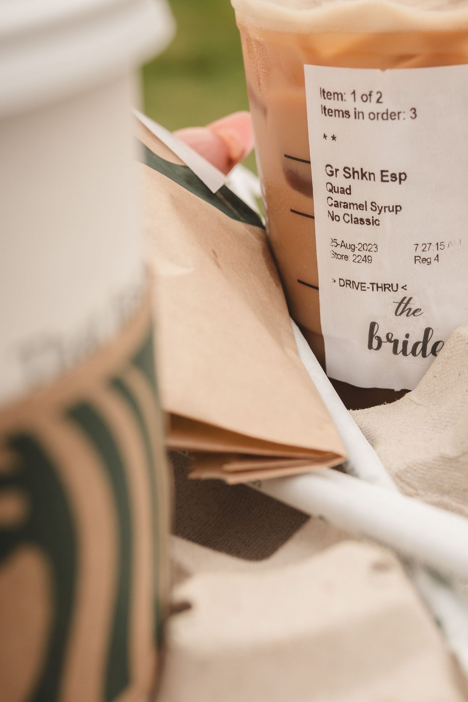 Close-up of a Starbucks coffee cup labeled for the bride with wedding details.
