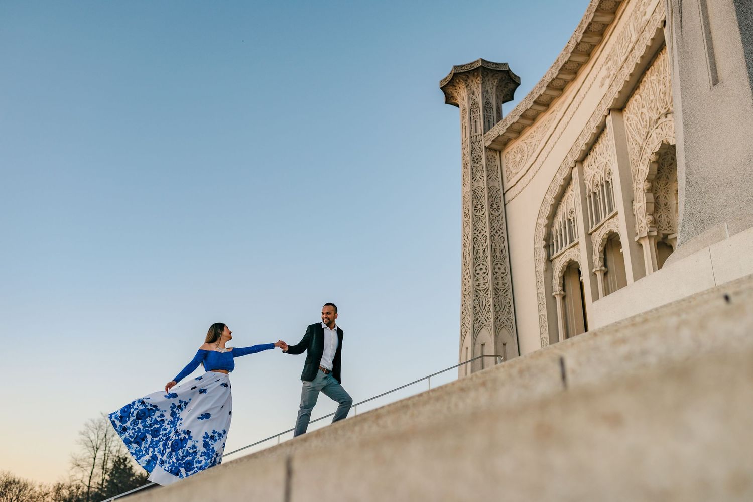Dancing pose against ornate white palace architecture during golden hour.