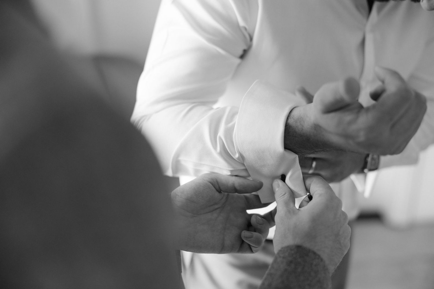Black and white close-up of hands exchanging wedding rings during ceremony.