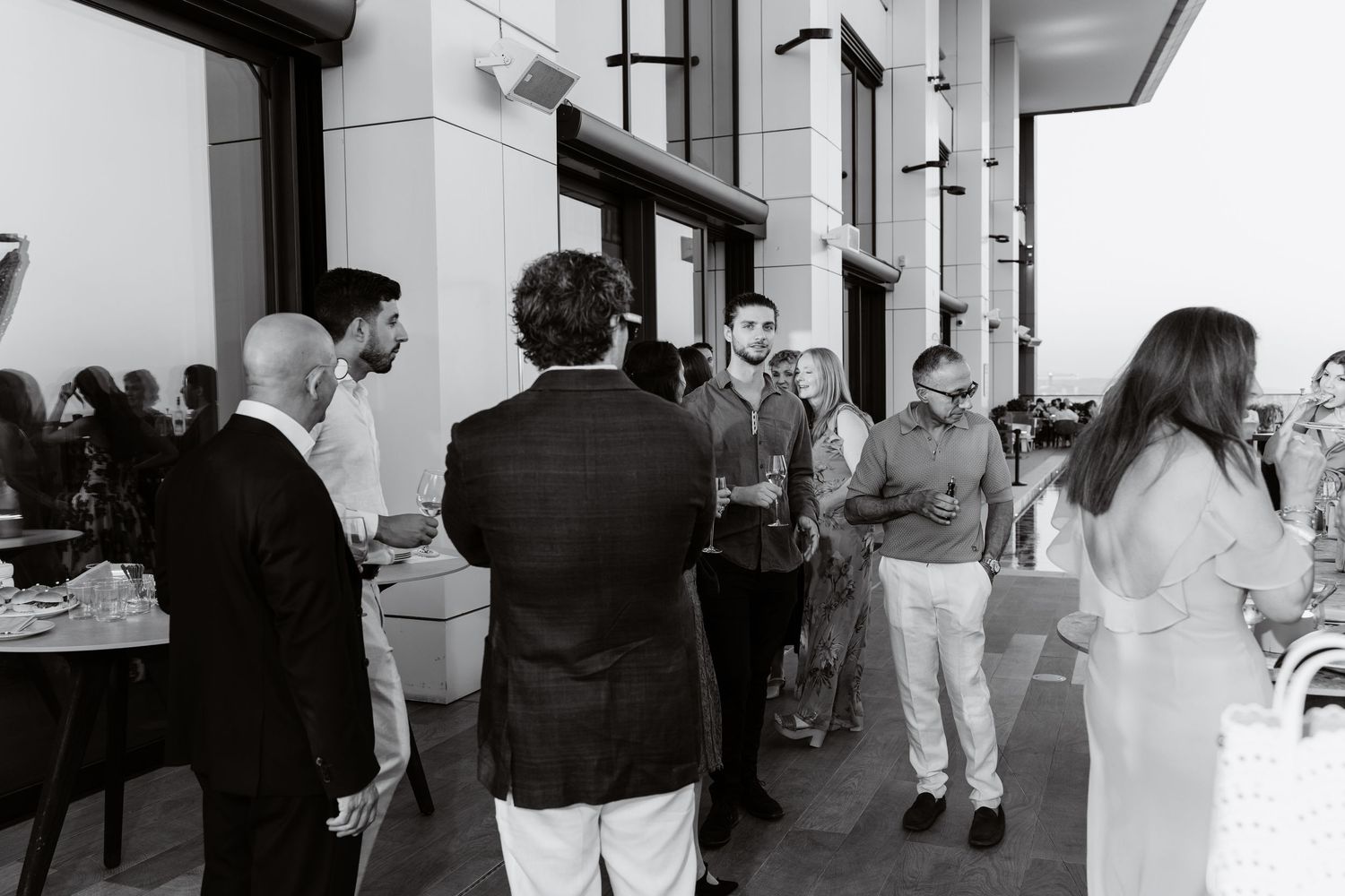 Black and white photo showing guests mingling at an elegant indoor social gathering.