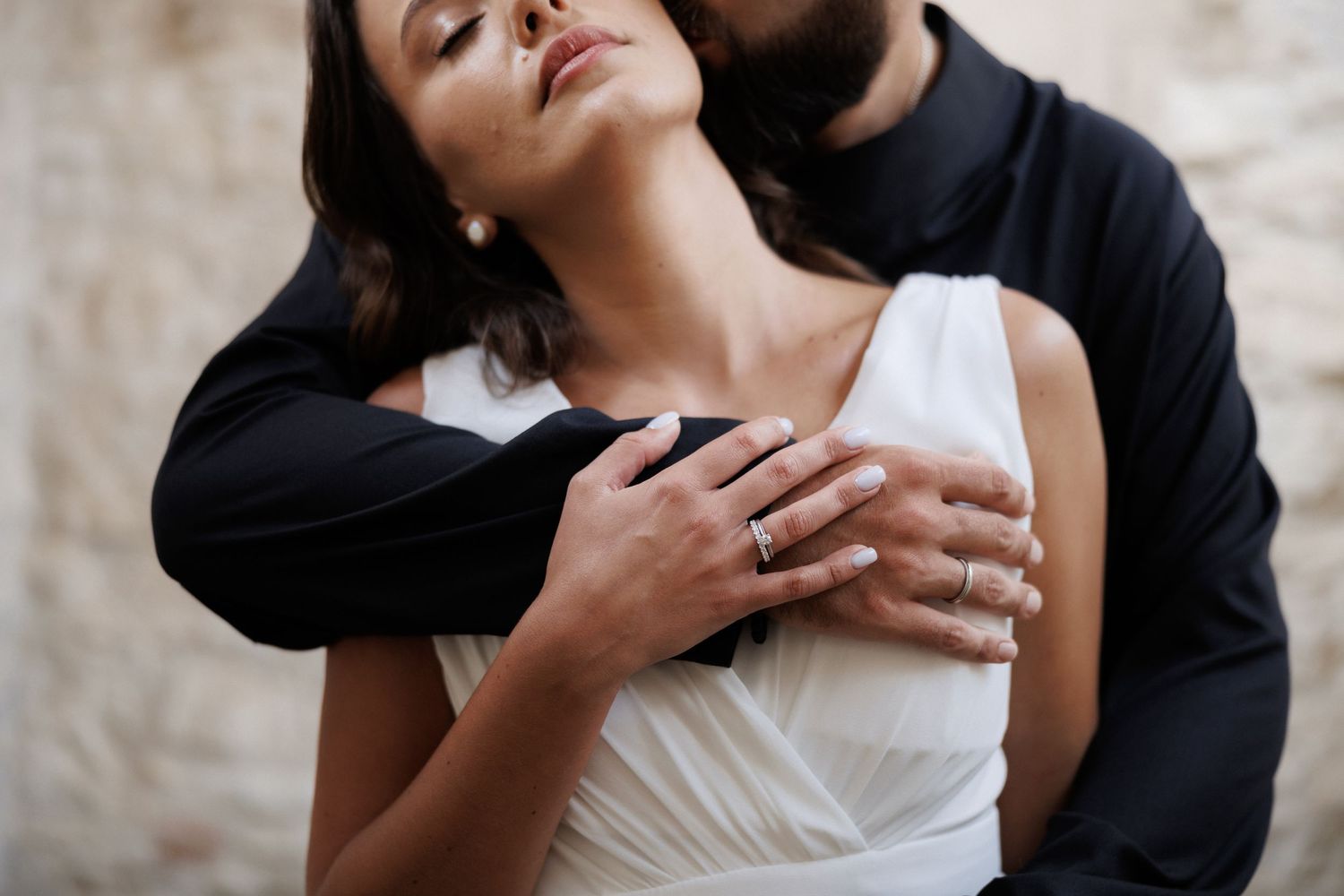 An intimate black and white portrait showing an embrace between a couple in formal attire.