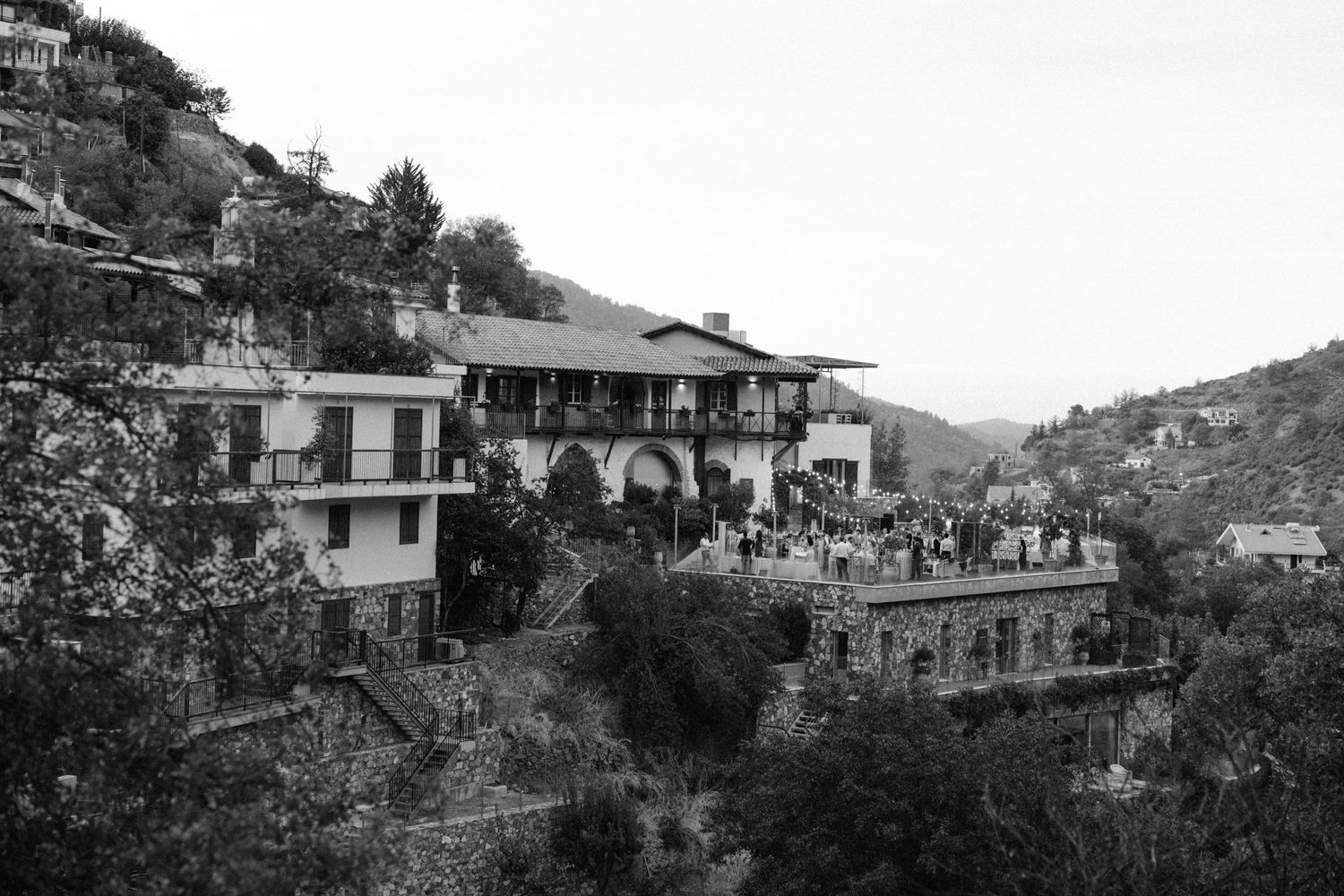 Historic hillside villa with terraced architecture nestled in a mountainous Mediterranean landscape.