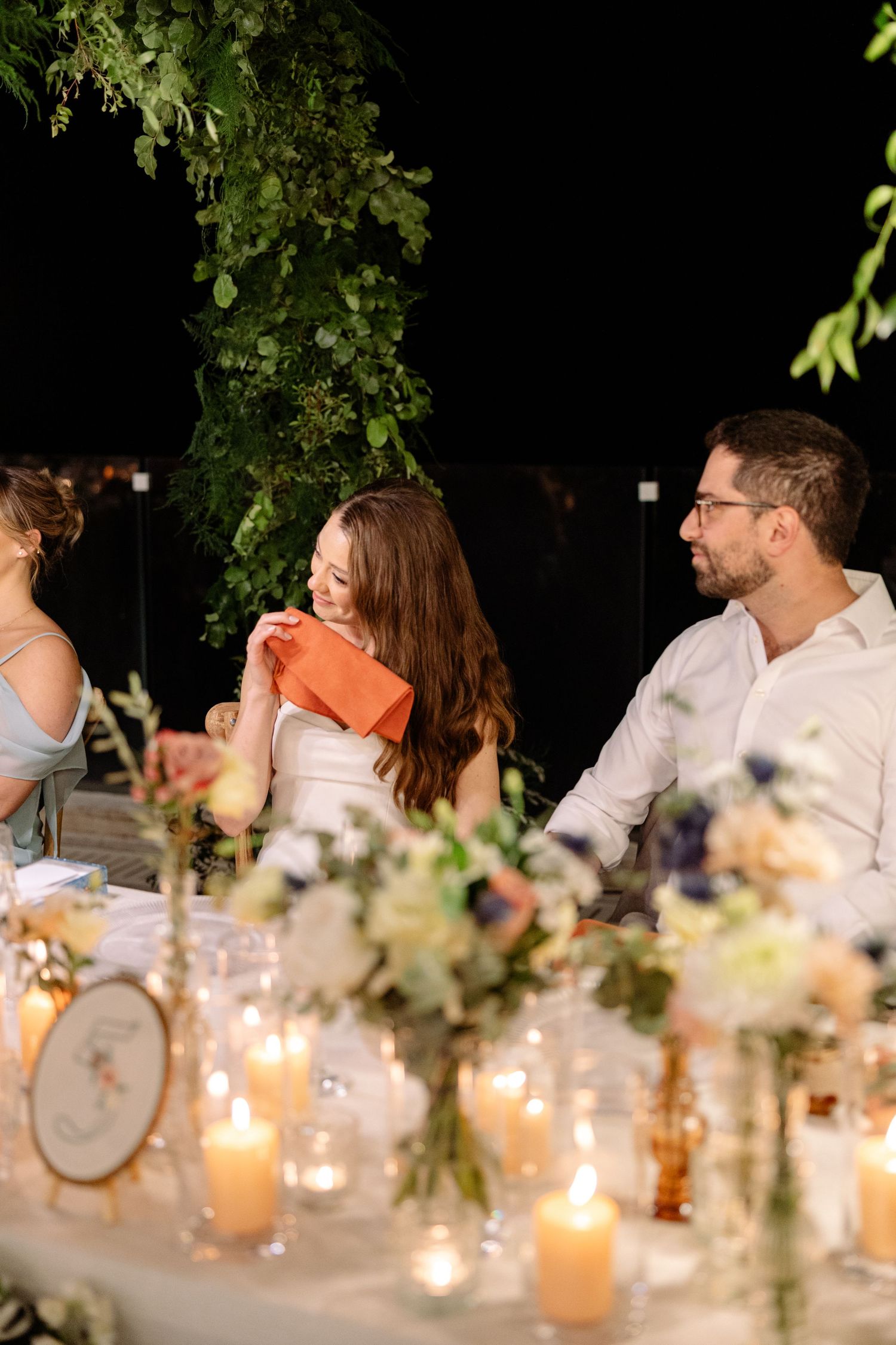 Intimate outdoor wedding reception table adorned with floral centerpieces and glowing candles.