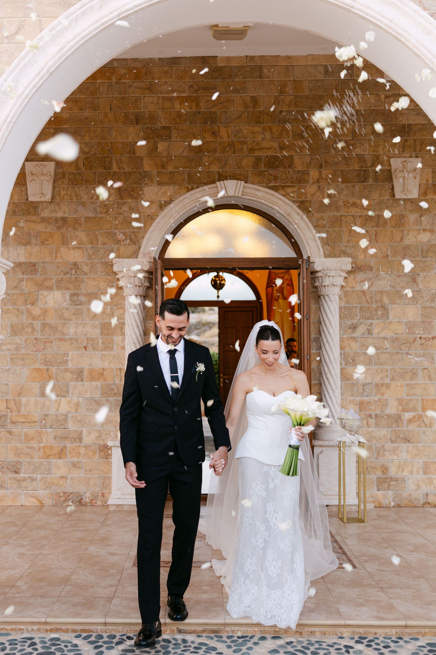 White flower petals falling in front of stone archway during wedding celebration.