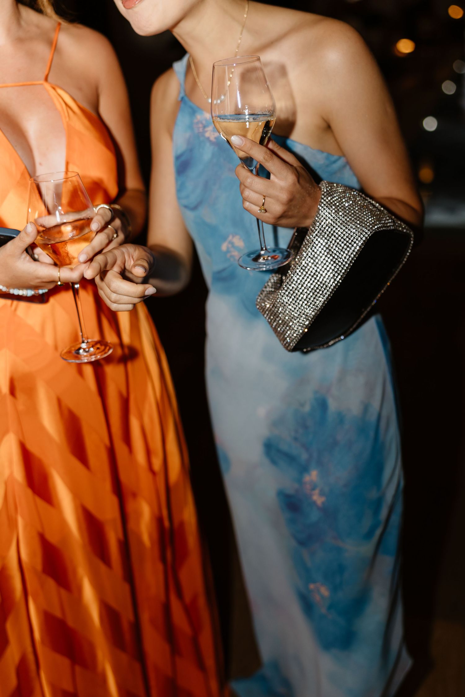 Close-up of formal dresses and champagne glasses at evening event.