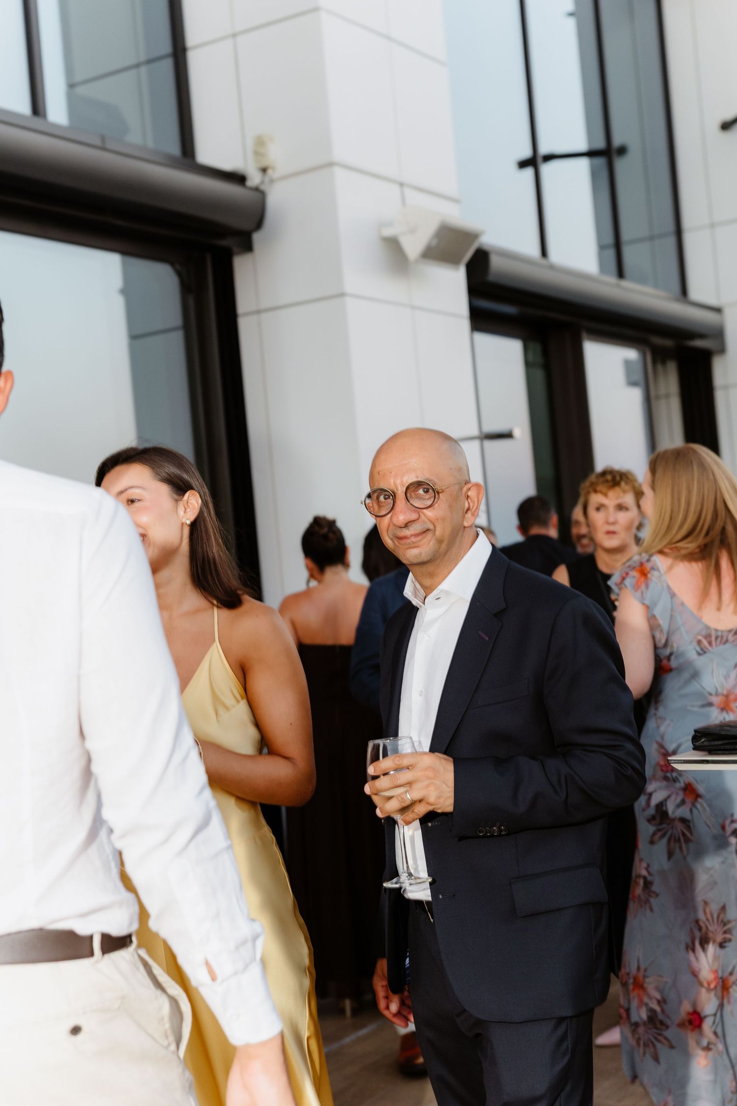 Guests mingling at outdoor cocktail reception with modern building backdrop.