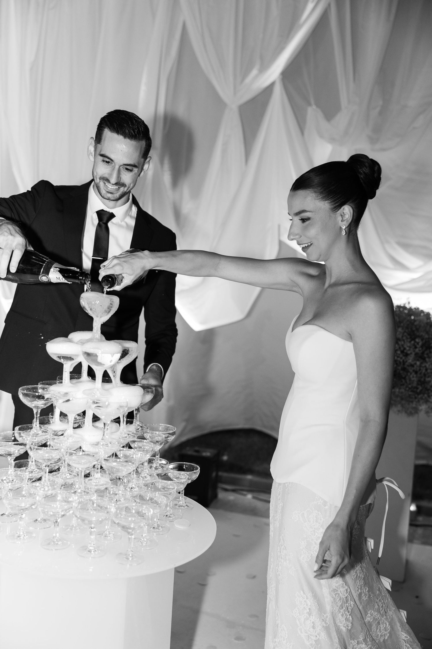 Champagne tower being carefully arranged at formal event with glasses in pyramid formation.