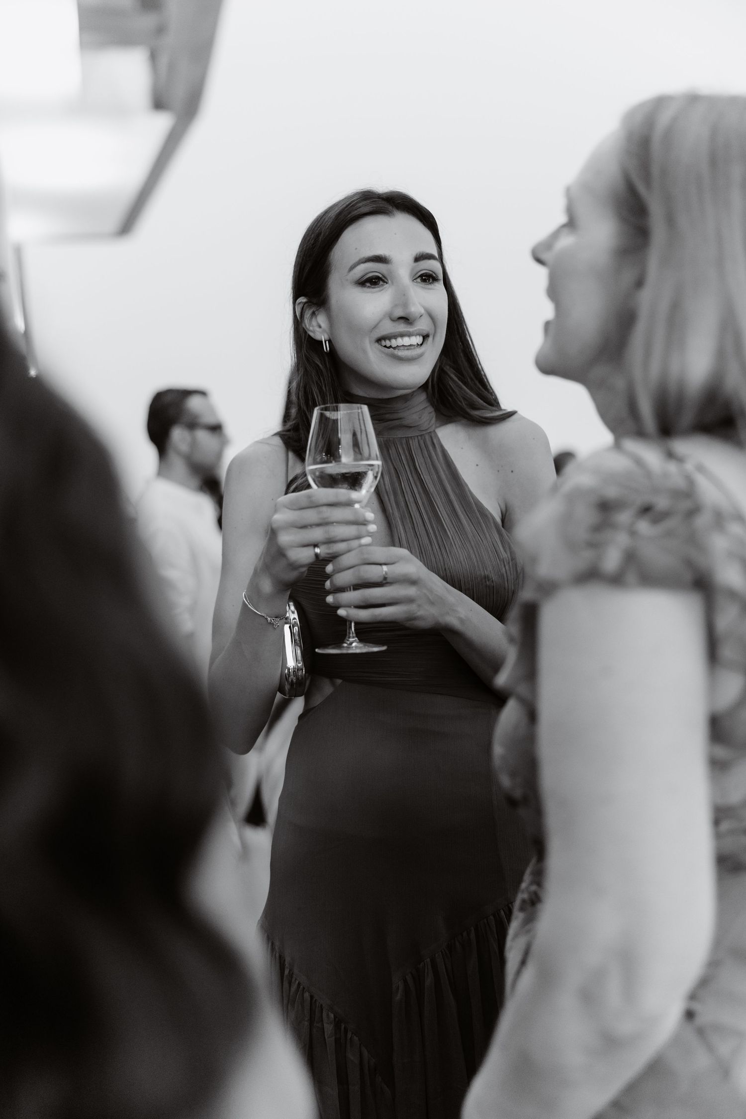 Guests enjoy drinks and conversation at an upscale social event in black and white photography.