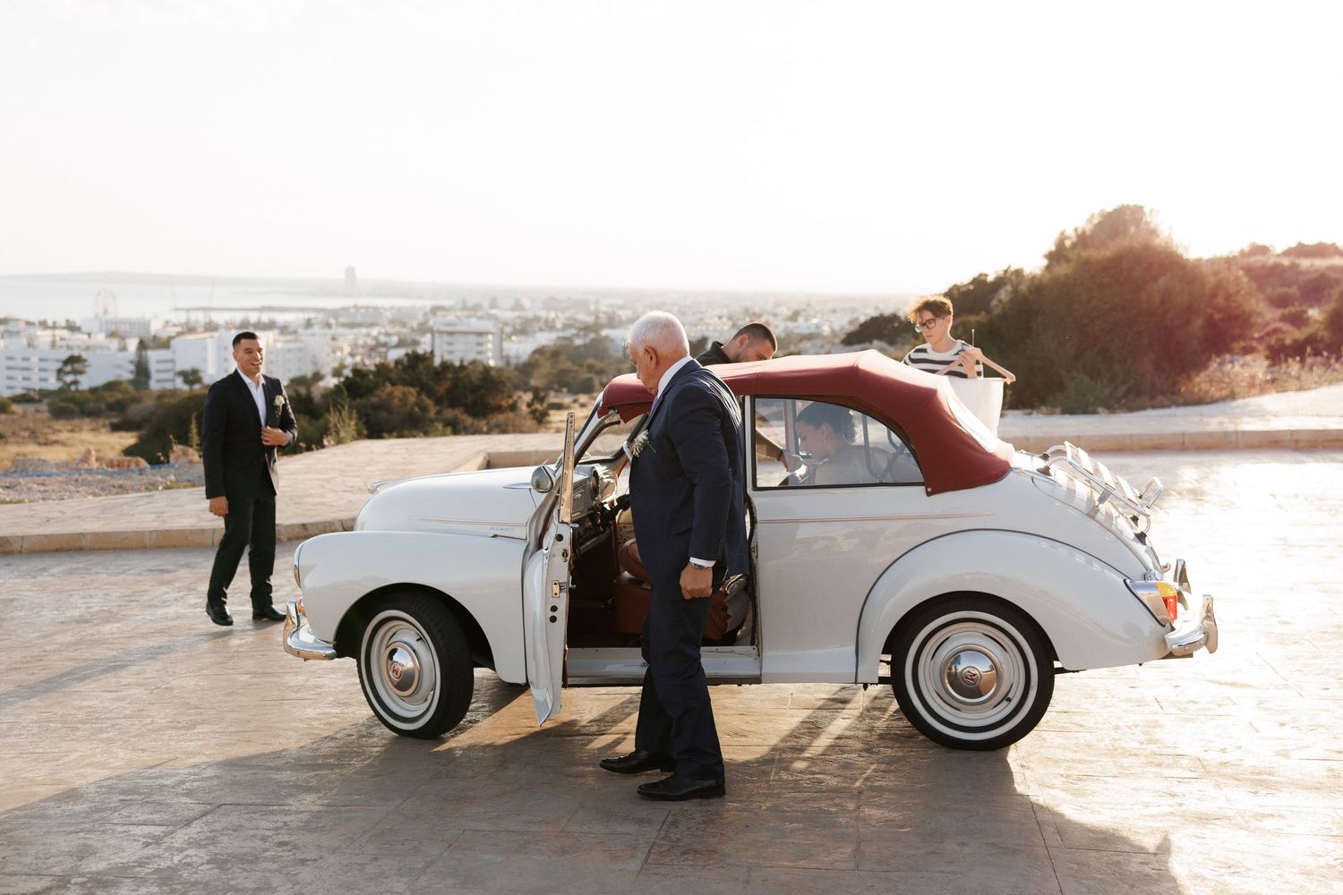 Vintage silver car parked outdoors at sunset with scenic mountain backdrop.