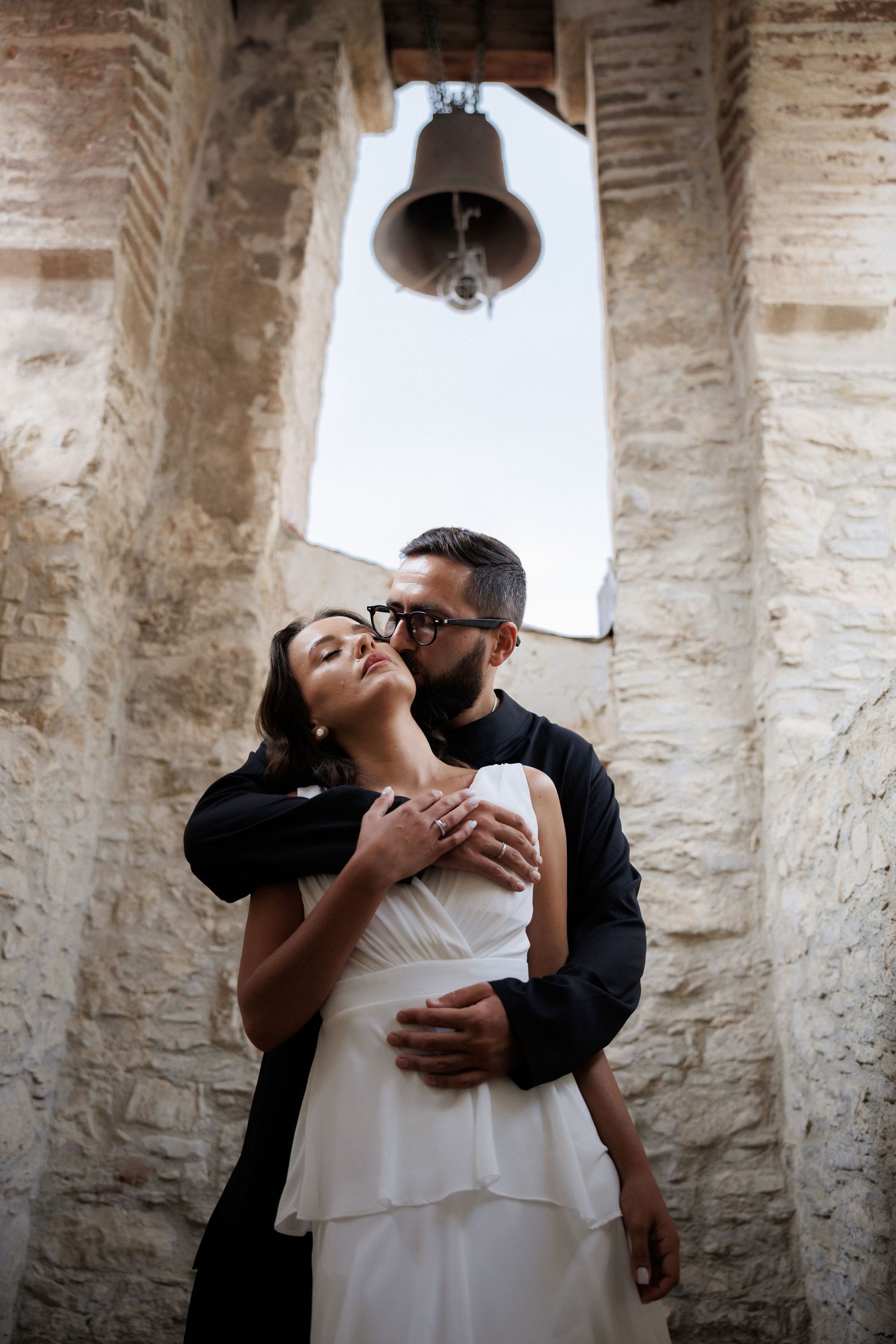 Romantic couple shares intimate moments in a sequence of tender embraces against a rustic stone archway background.