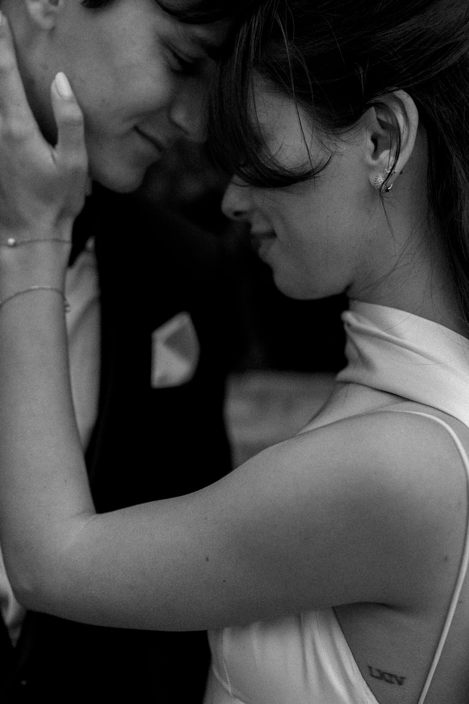 A romantic black and white close-up portrait of a couple sharing an intimate moment in formal attire.