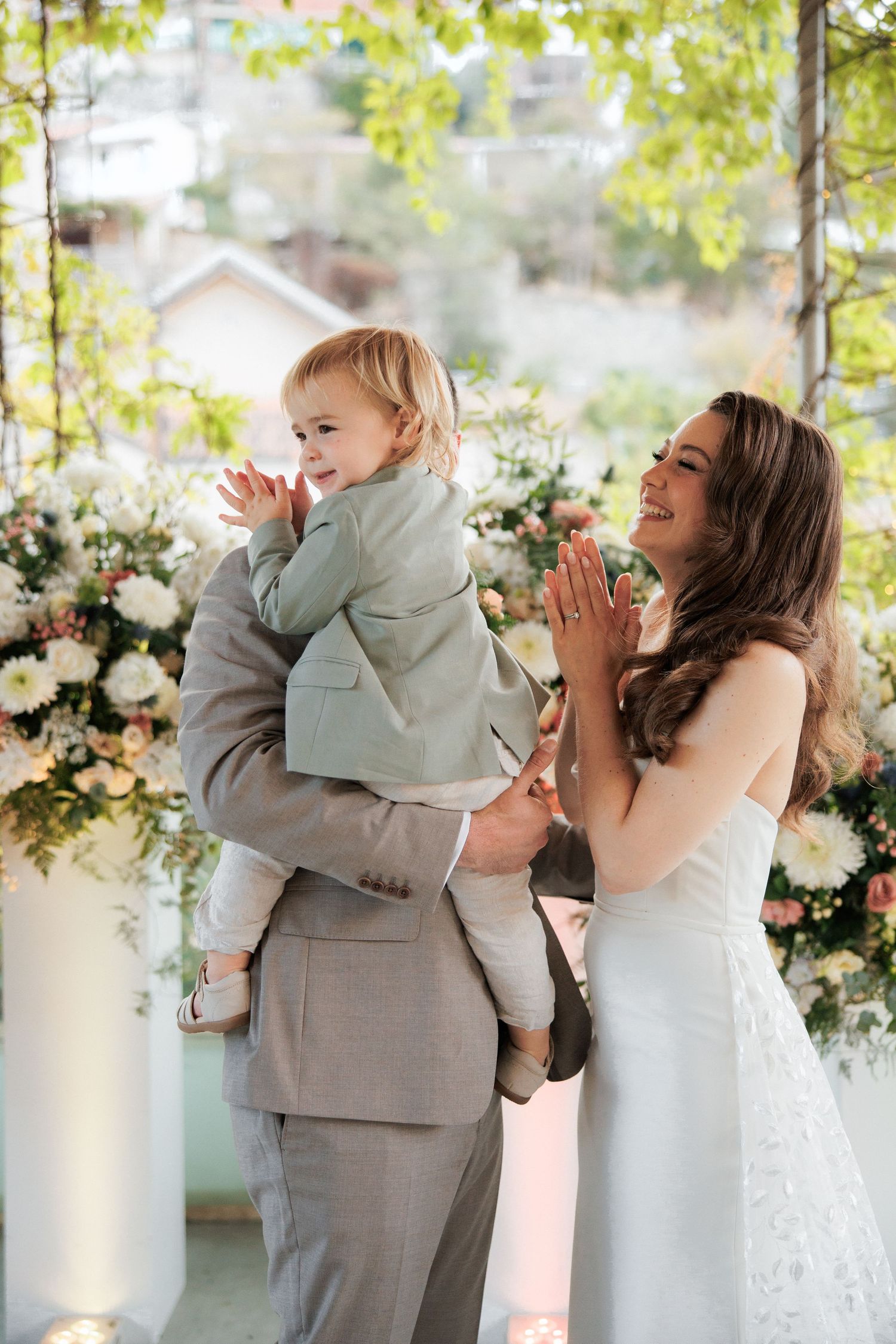 Joyful moment during wedding ceremony with floral backdrop and natural lighting.