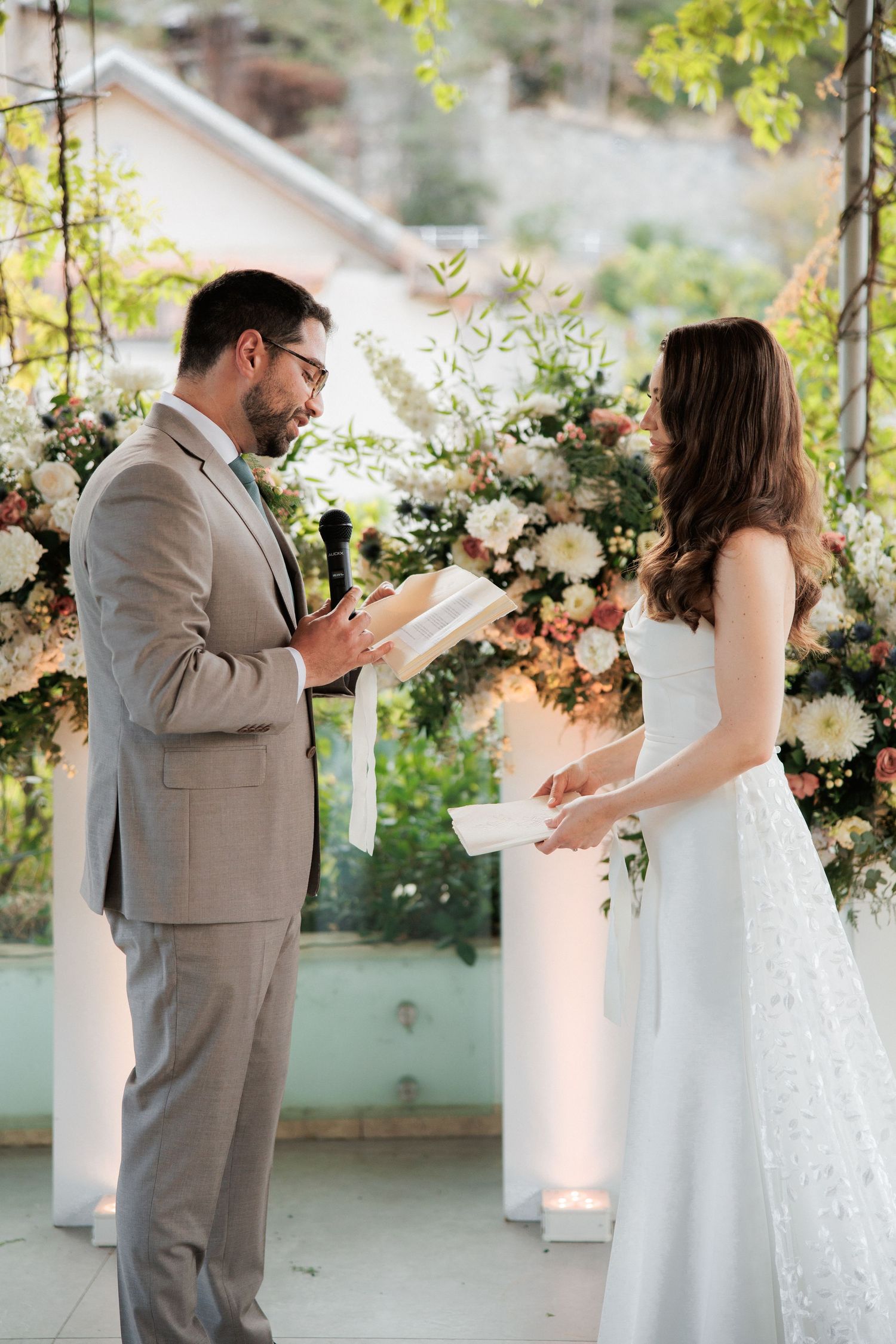 Couple exchanging vows during an intimate outdoor wedding ceremony surrounded by floral arrangements.