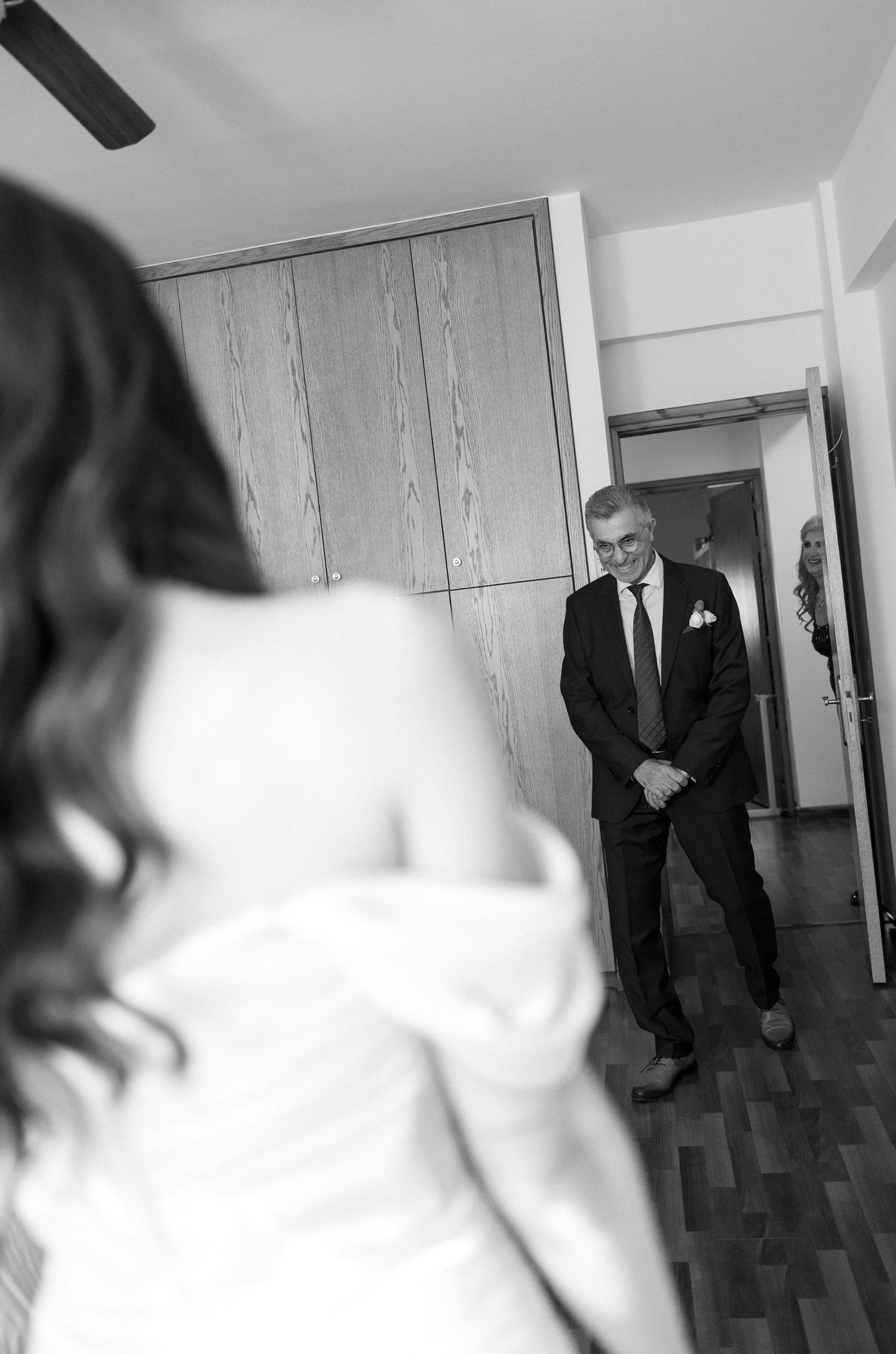 Black and white photo of a father seeing his daughter in her wedding dress for the first time, emotional first look moment.